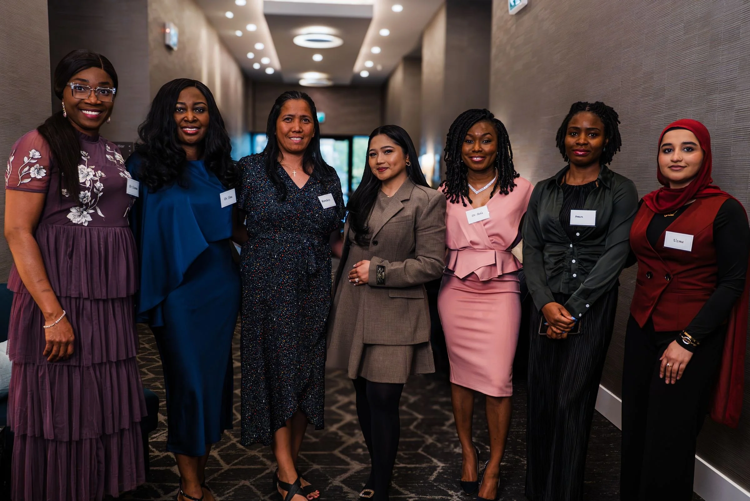 Seven women pose together for a group portrait at the Synergy Family Clinic dinner.