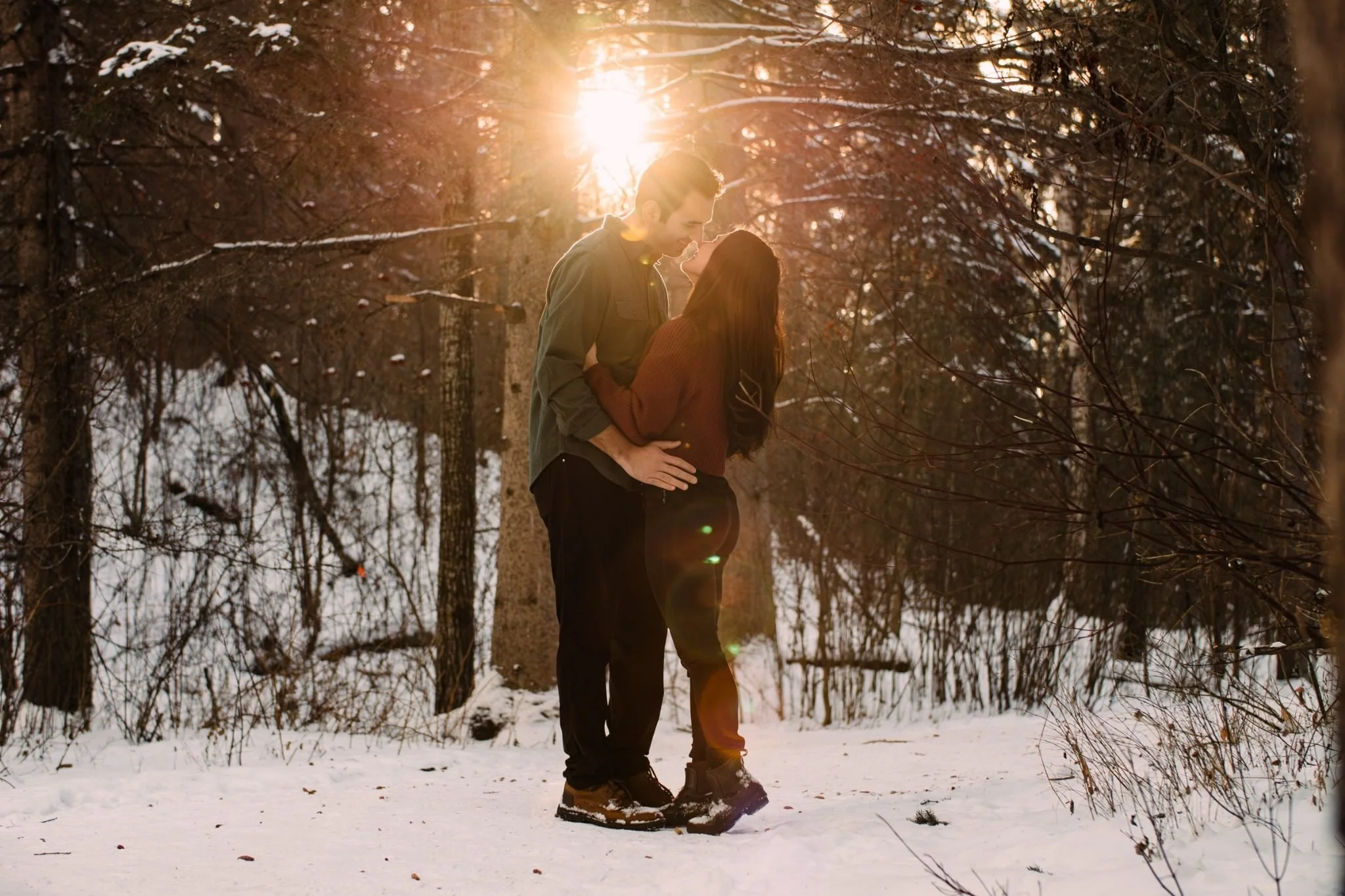 Engaged couple standing together in the snow at Whitemud Ravine during an Edmonton engagement photography session by Kevin M Films.