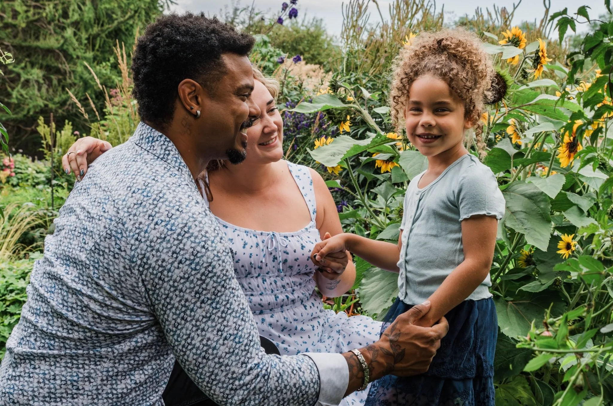 Family smiling together among the gardens at St. Albert Botanic Park during an Edmonton family photography session by Kevin M Films.