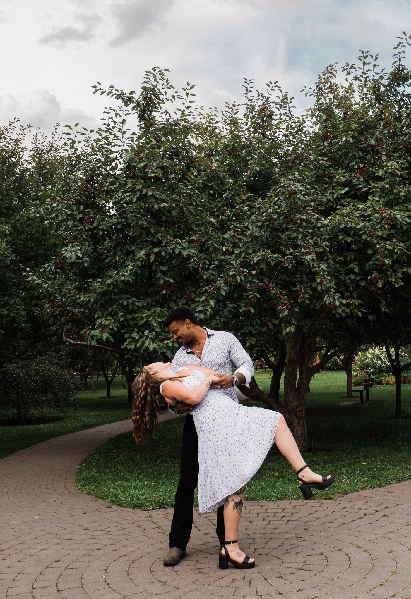 Engaged couple laughing during a dip pose at St. Albert Botanic Park, photographed by Kevin M Films.