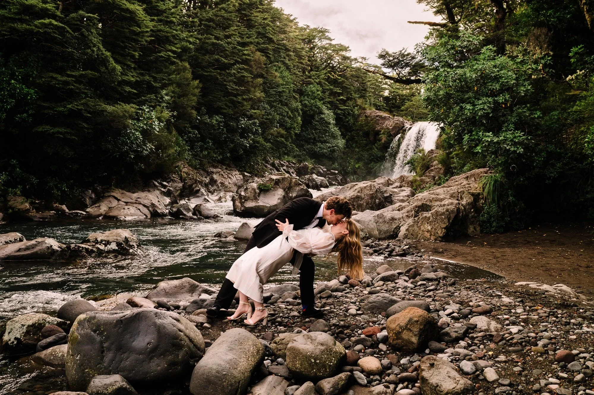 New Zealand styled elopement couple kissing in front of a waterfall, photographed by Kevin M Films.