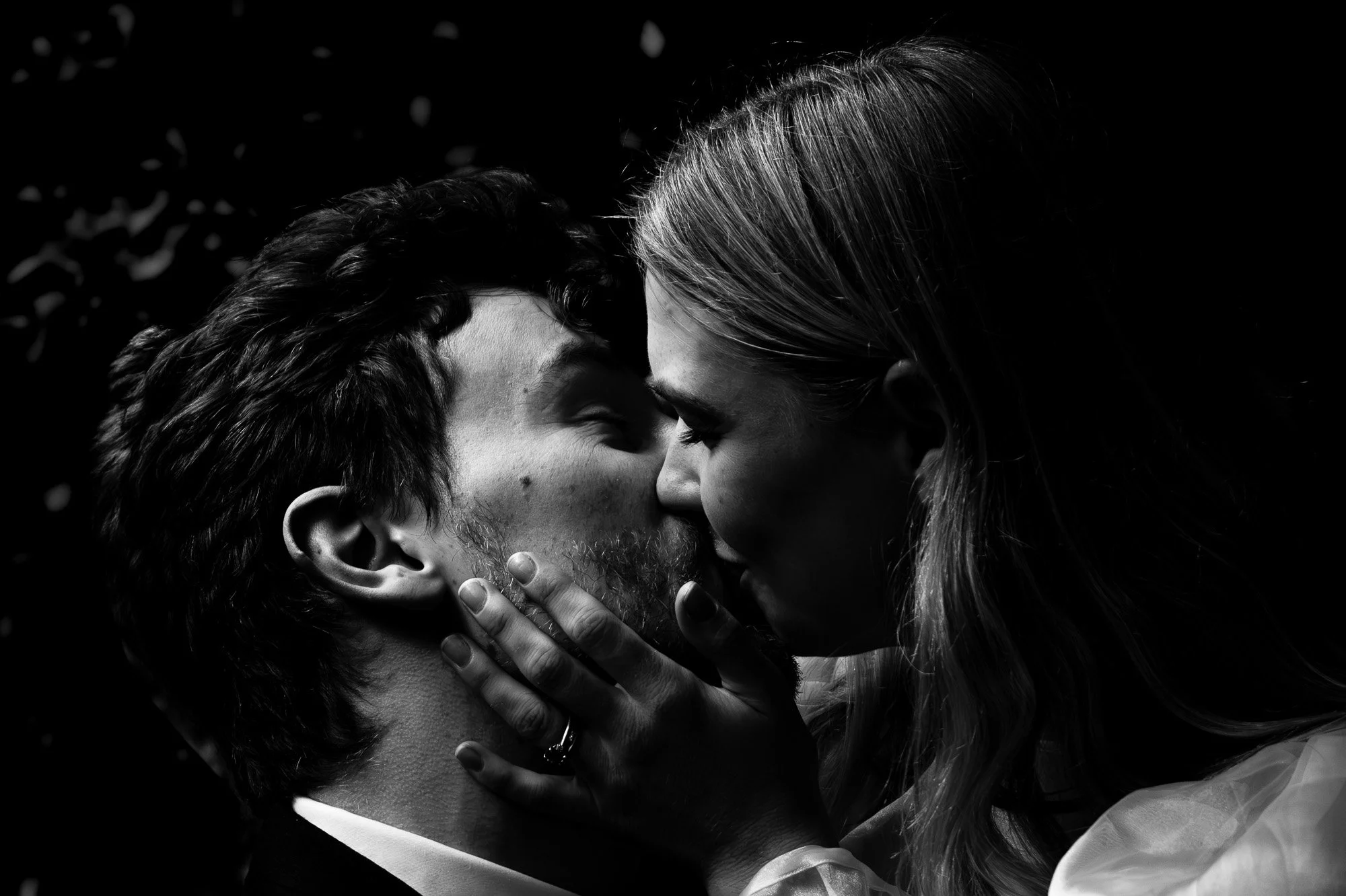 Black-and-white close-up of a styled elopement couple kissing near Tawhai Falls in New Zealand, photographed by Kevin M Films.