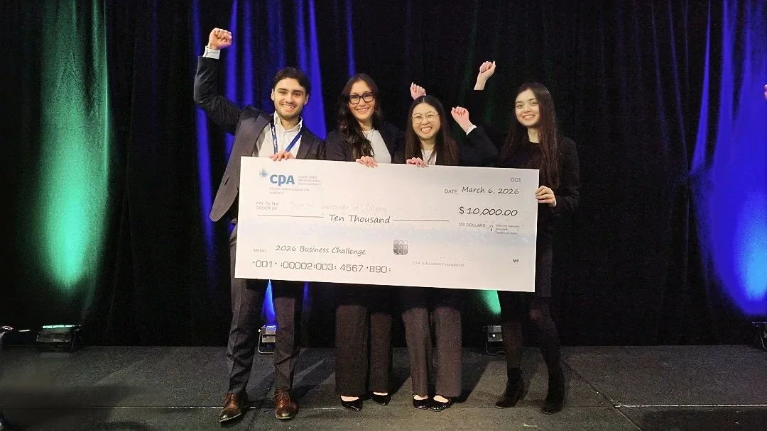 Four participants celebrate on stage with an oversized $10,000 cheque for the 2026 Business Challenge.