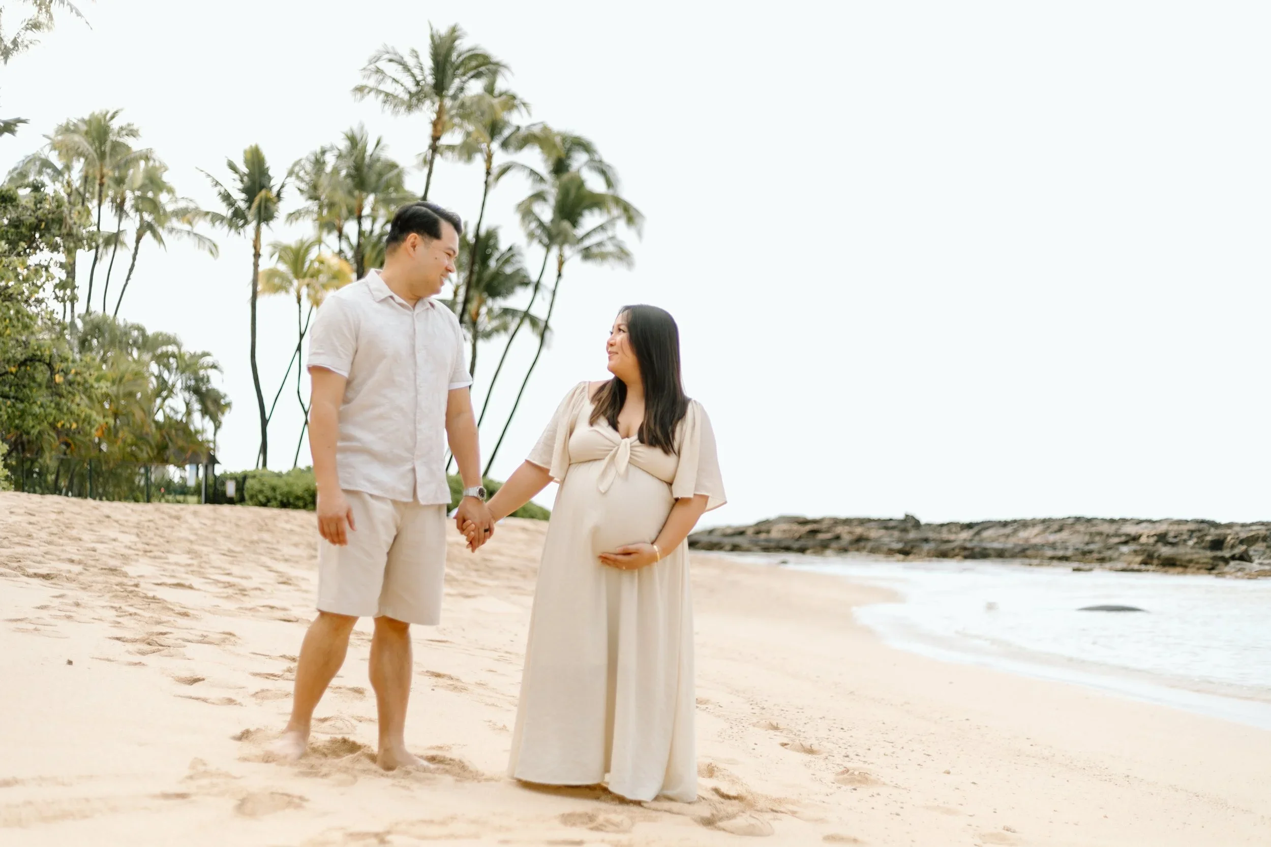 Oahu babymoon maternity photography session featuring a couple on a white sandy beach during their babymoon on Oahu
