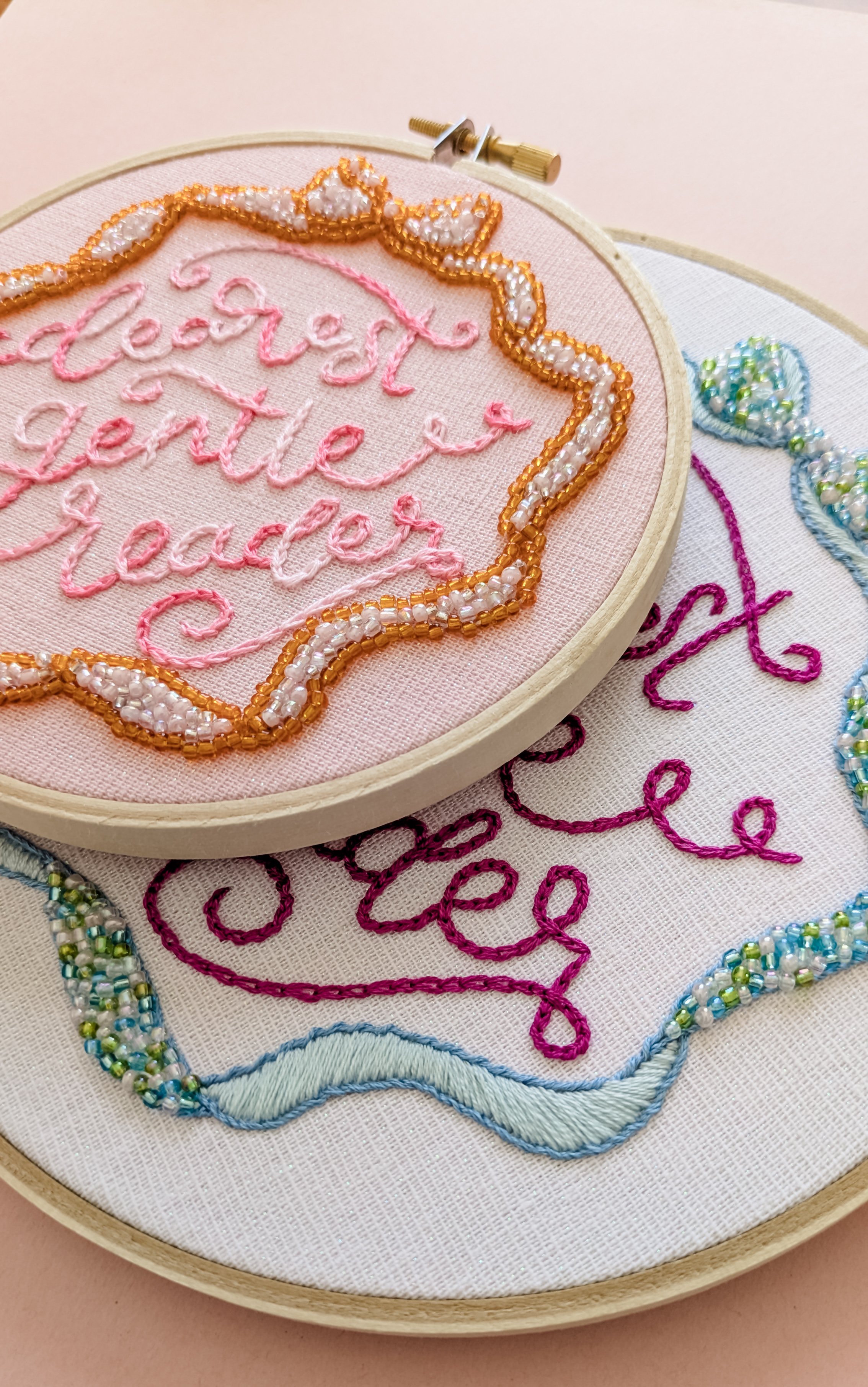 Embroidery hoops with colorful designer embroidery designs of words and floral patterns on fabric.