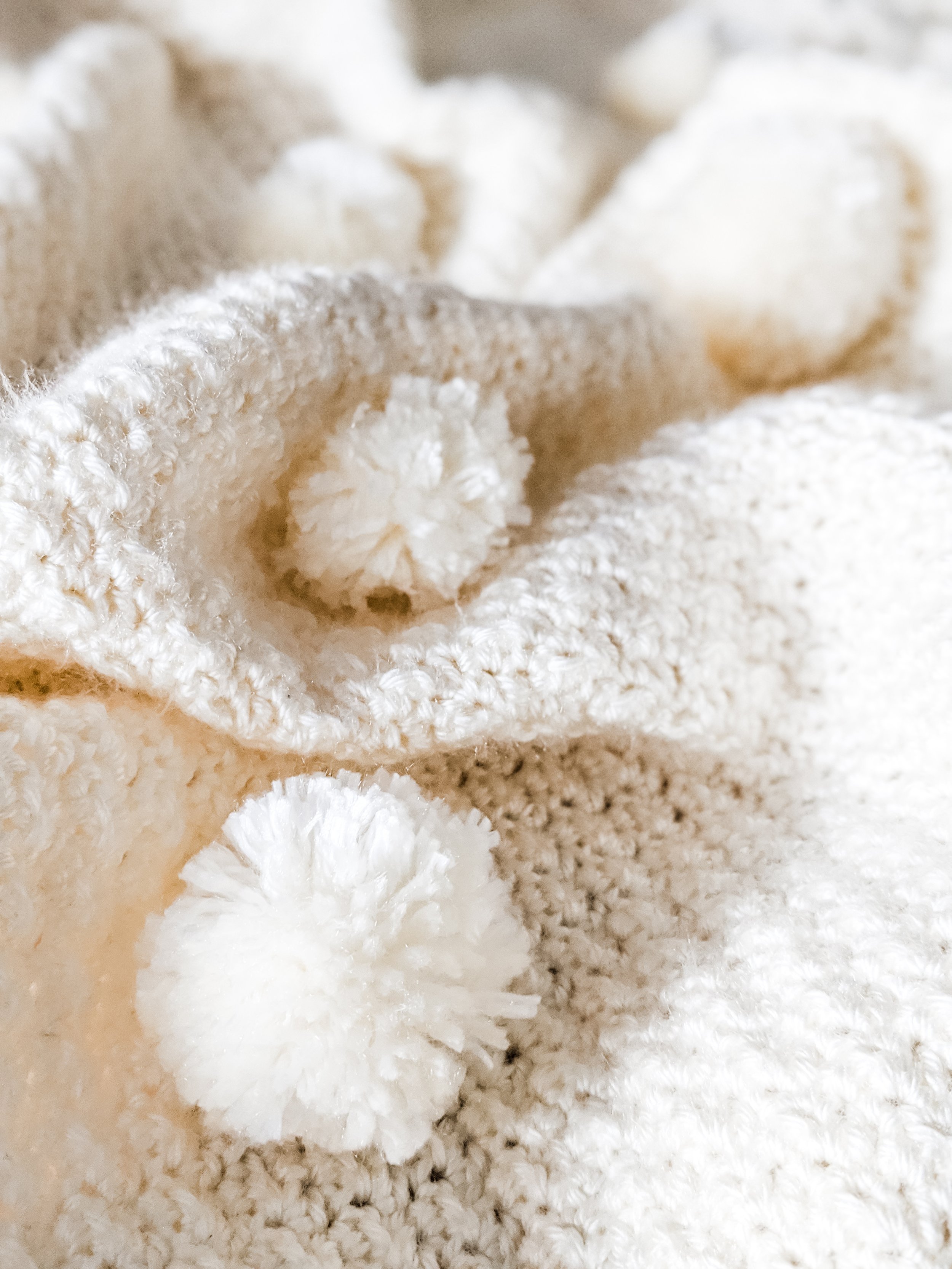 Close-up of fluffy white cotton bolls with soft, textured surface and delicate fibers on a crochet blanket.