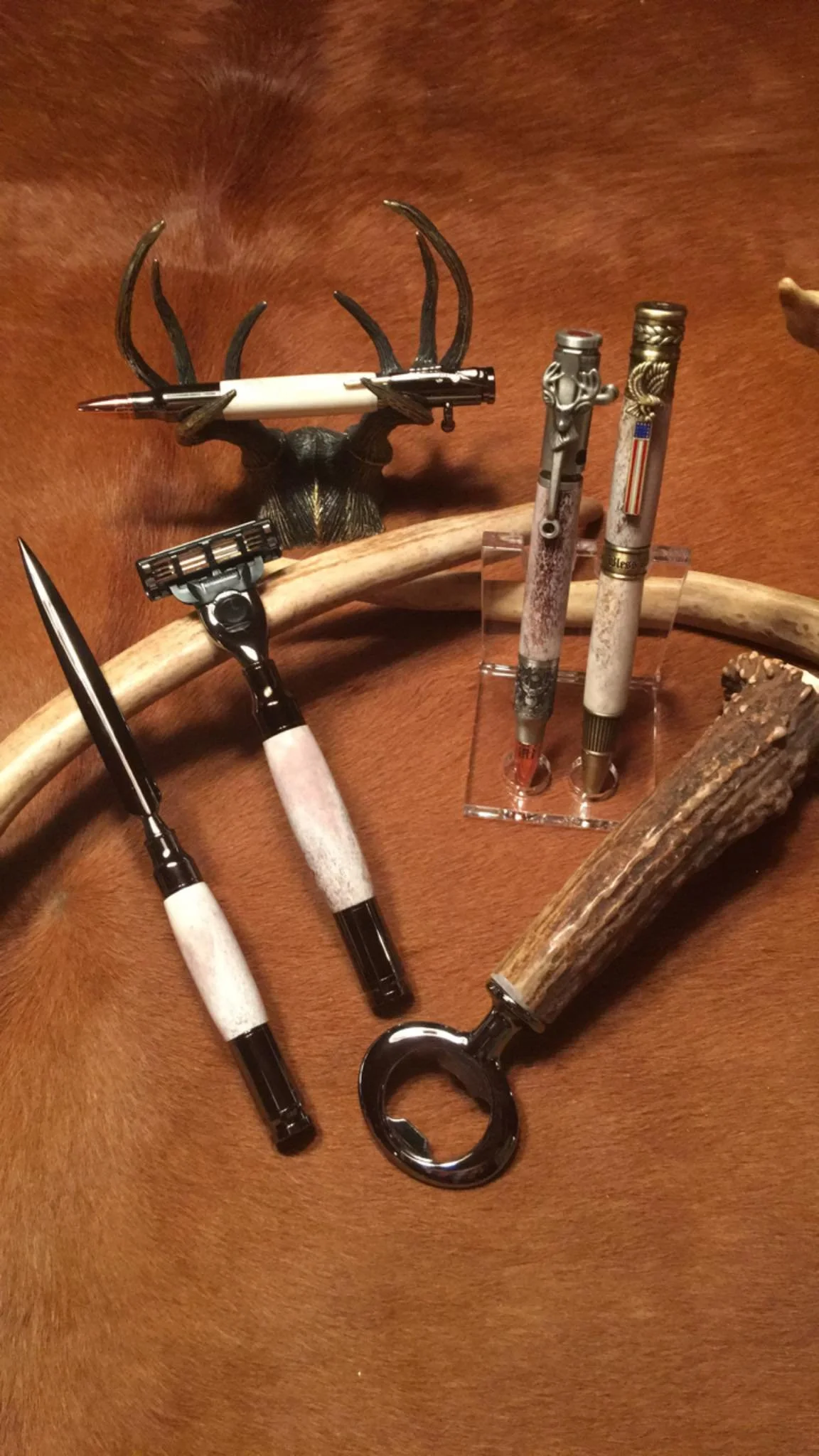 Collection of vintage pens and knives displayed on mannequin or animal hide background.