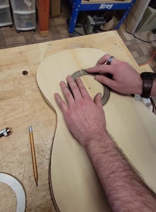 a student inserts a rosette into carved channel in a new guitar front plate at heritage luthier school in lexington north carolina with luthier john vergara