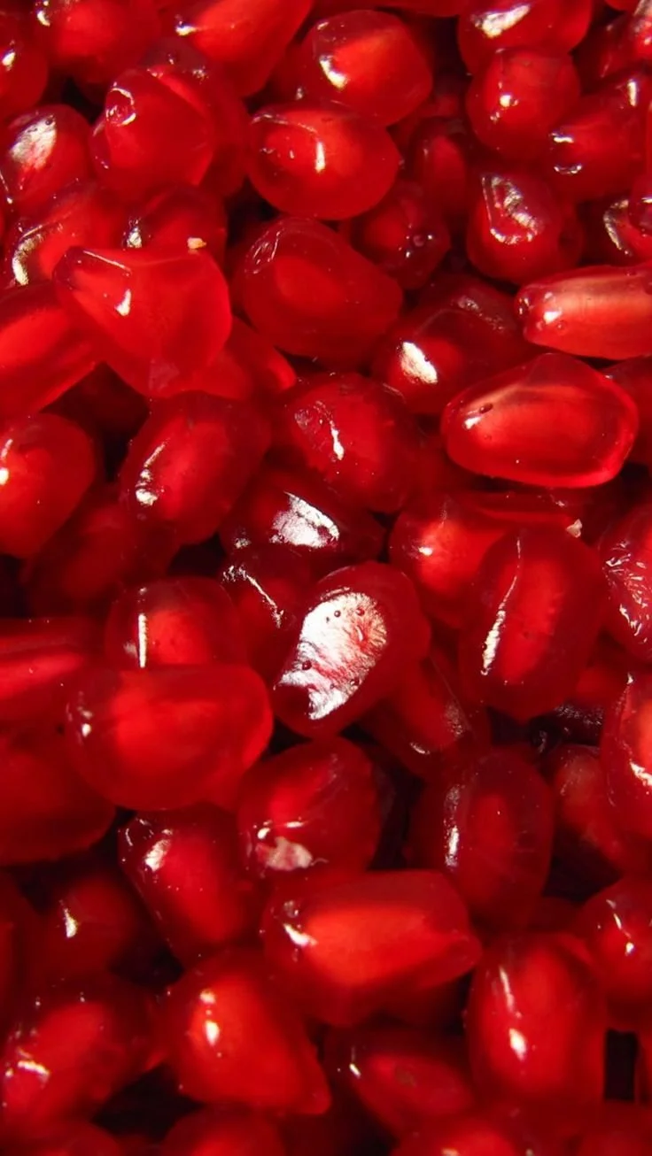 Close-up of numerous red pomegranate seeds.