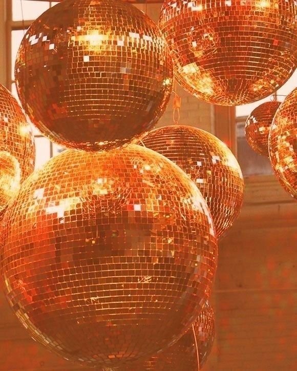 Multiple large orange disco balls hanging from the ceiling, reflecting light and creating a shiny, festive atmosphere.