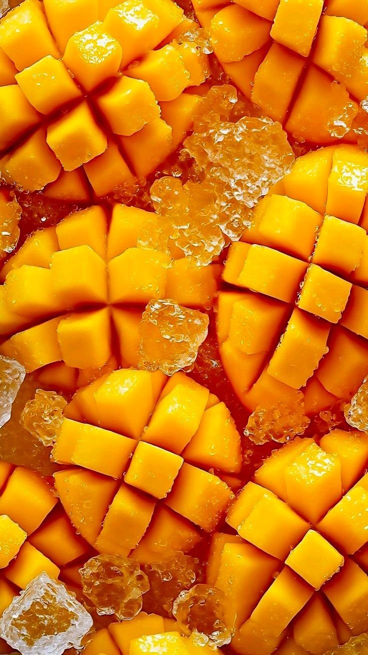 Close-up of cubed mangoes with ice cubes scattered on top.