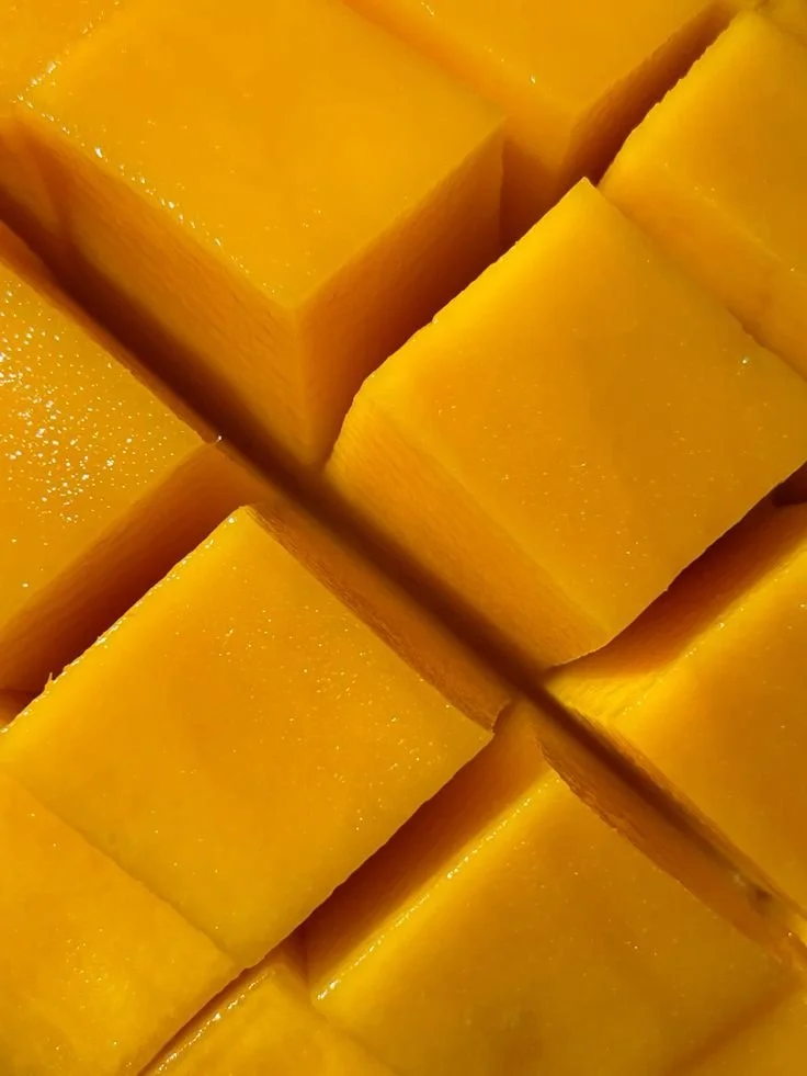Close-up of multiple fresh, bright yellow mango chunks.