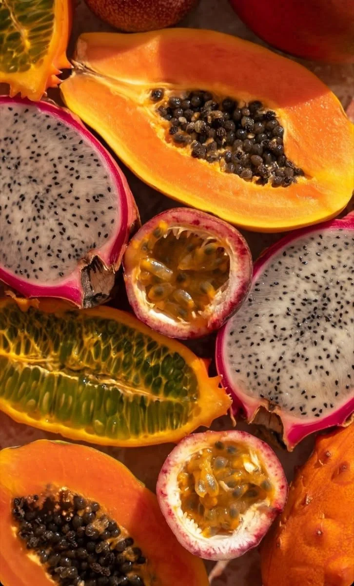 Assorted sliced tropical fruits including papaya, dragon fruit, passion fruit, kiwi, and orange.