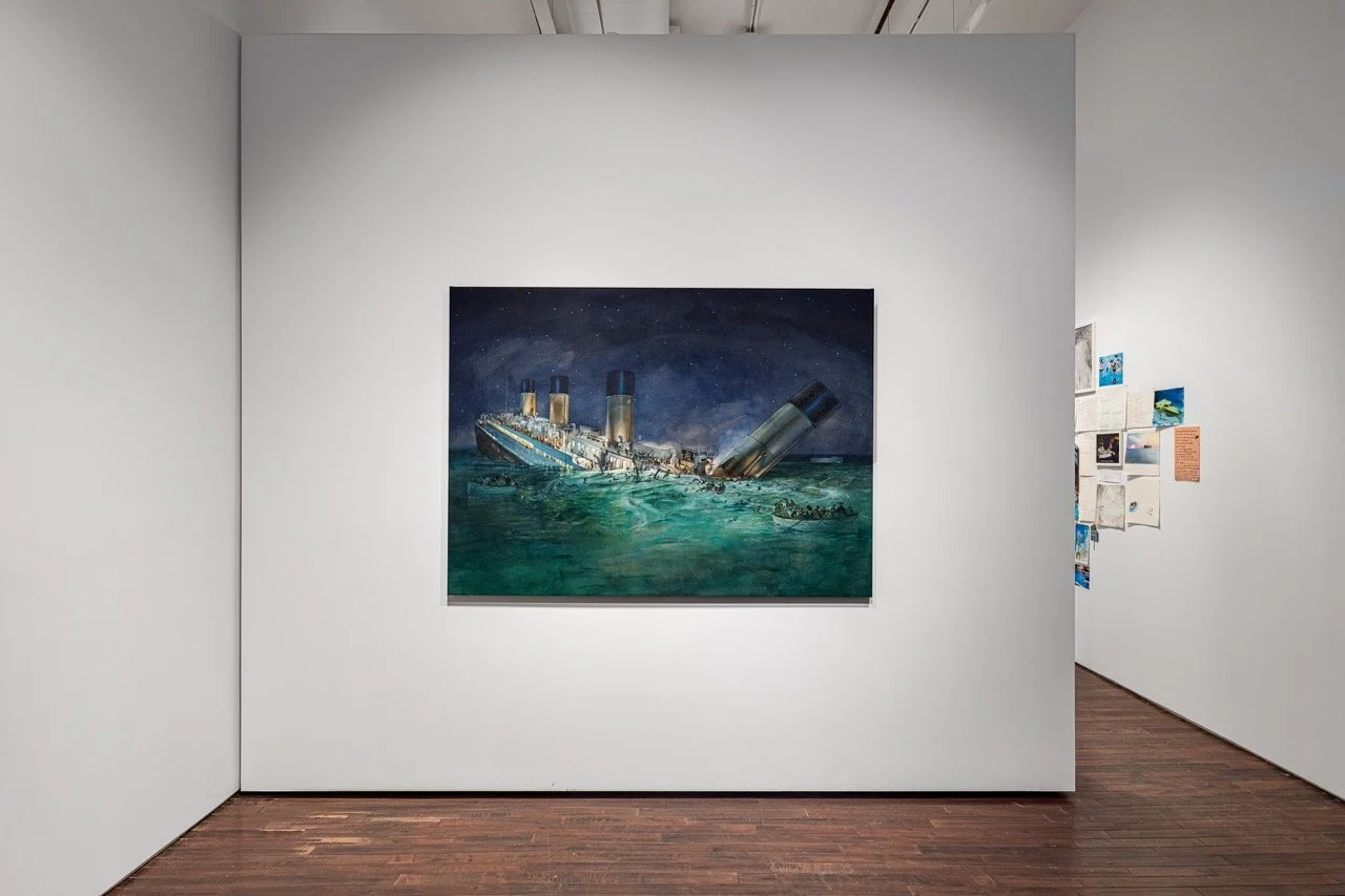 Gallery installation view with a large painting of the Titanic sinking in teal waters on a white wall, with a paper collage visible in the adjoining room.