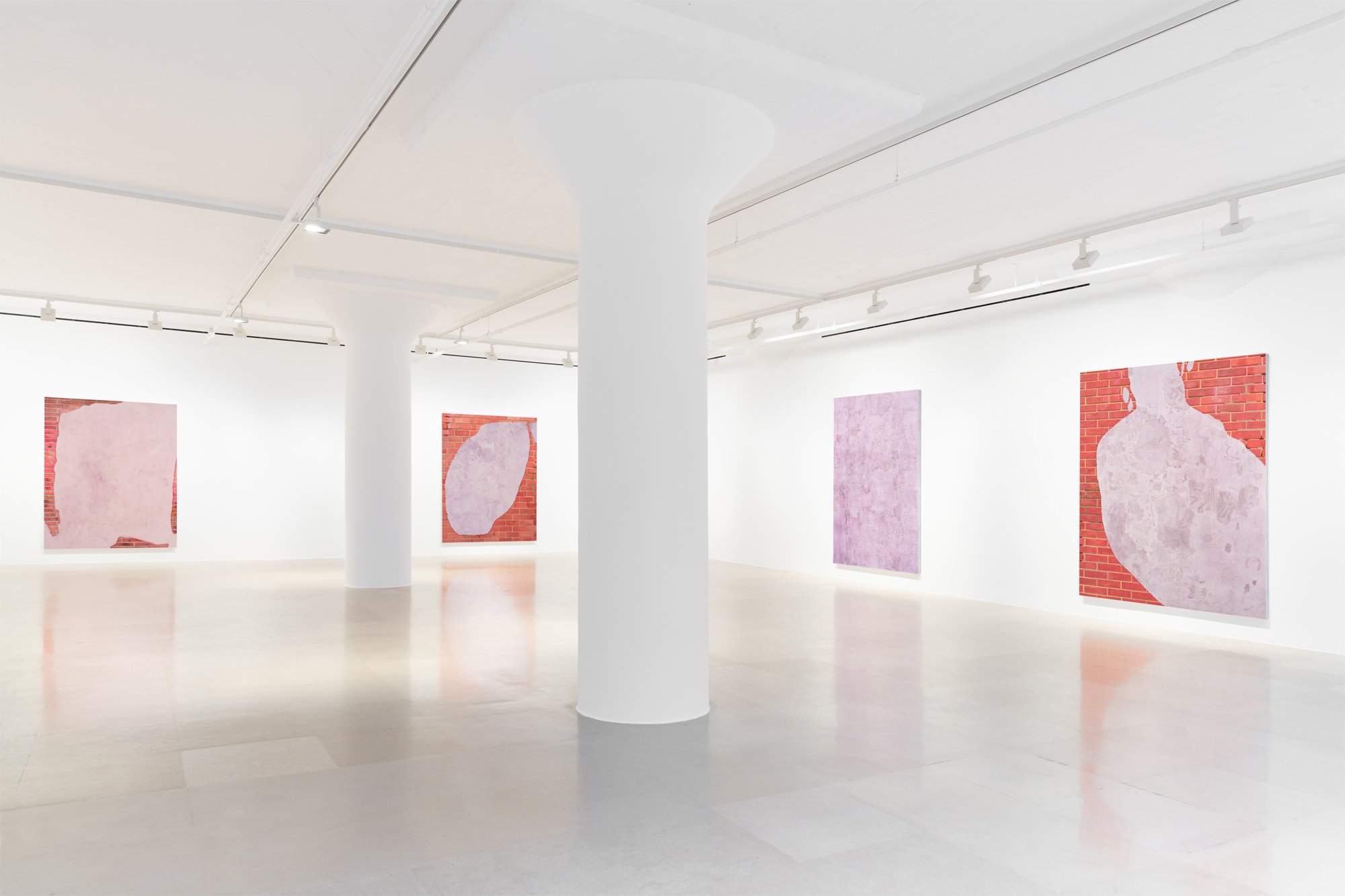 A large white gallery room with white columns features four large 2D works on two walls. Each work features a lavender palette, some with a fake brick background.