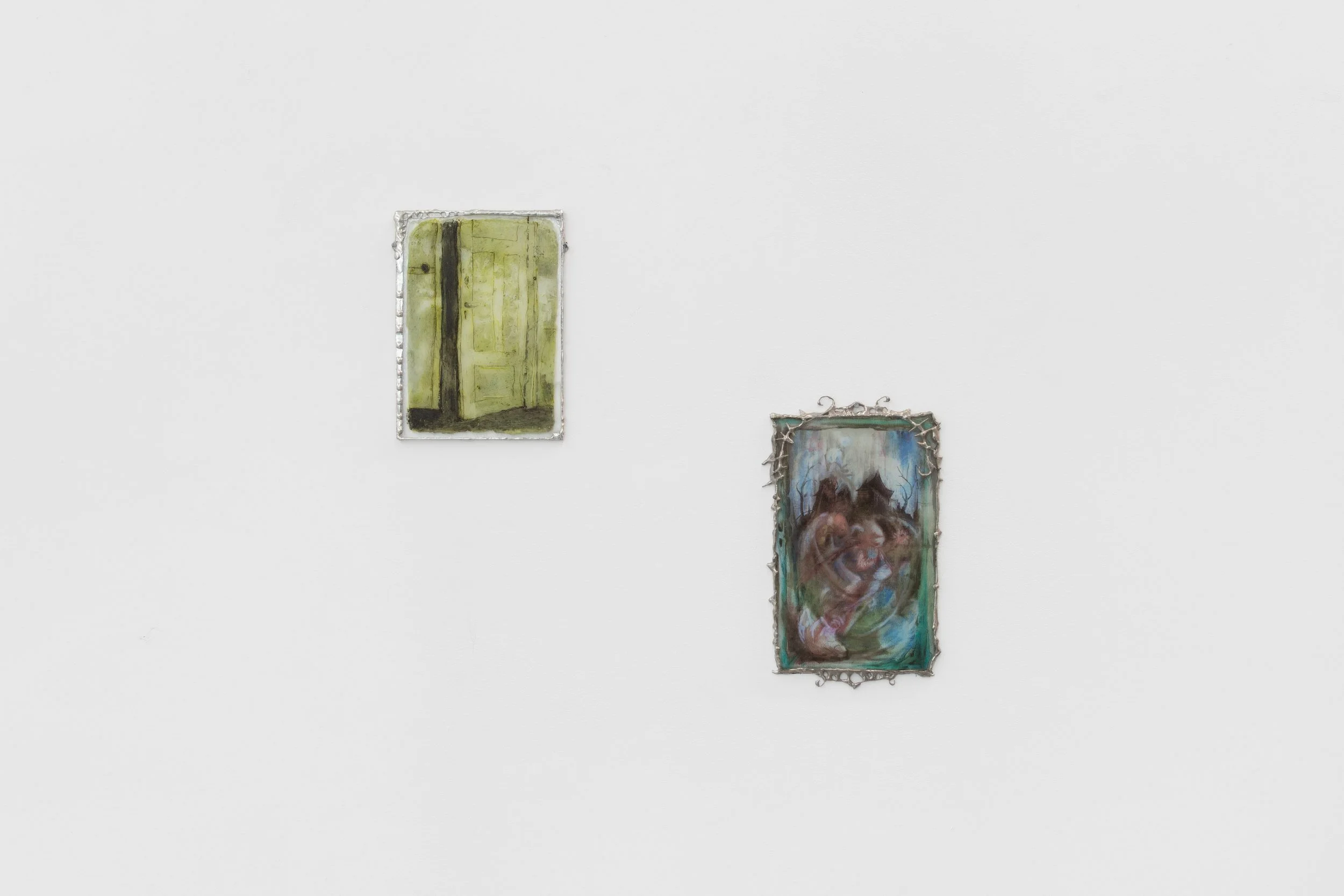 Two small, rectangular wall works hang diagonally apart from each other. Each has an ornate, spindly, sculptural silver frame. The subject matter is painted in soft washes of green, blue, and dusty red.