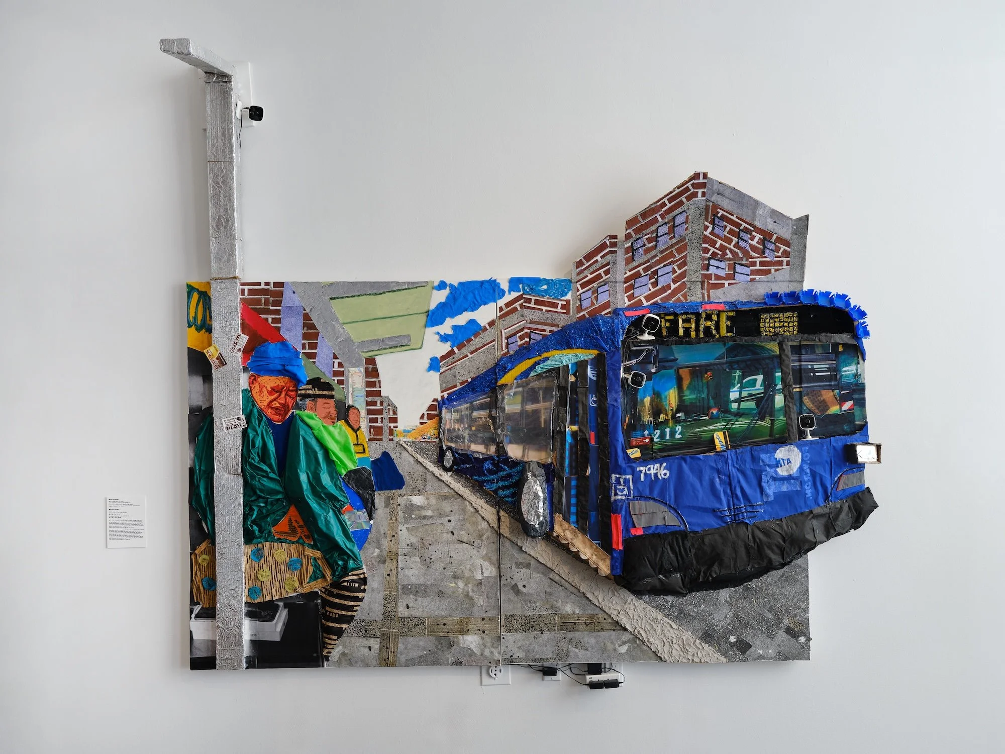 Large mixed-media wall collage depicting a blue city bus and bundled figures against brick buildings and a street scene.