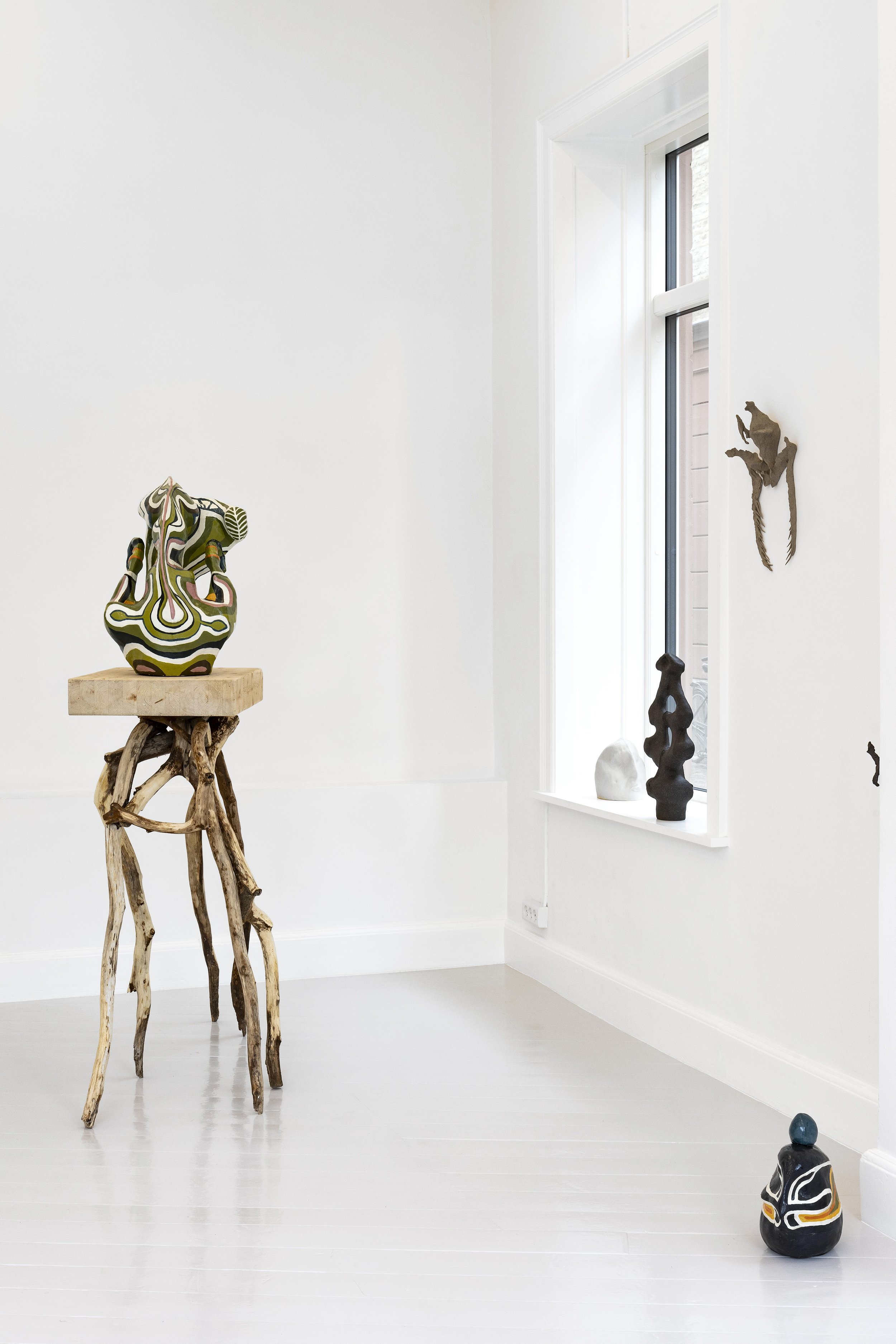 Several sculptural works populate the walls and floor space of a gallery. The rest on windowsills, plinths, and walls. Each echo organic forms.