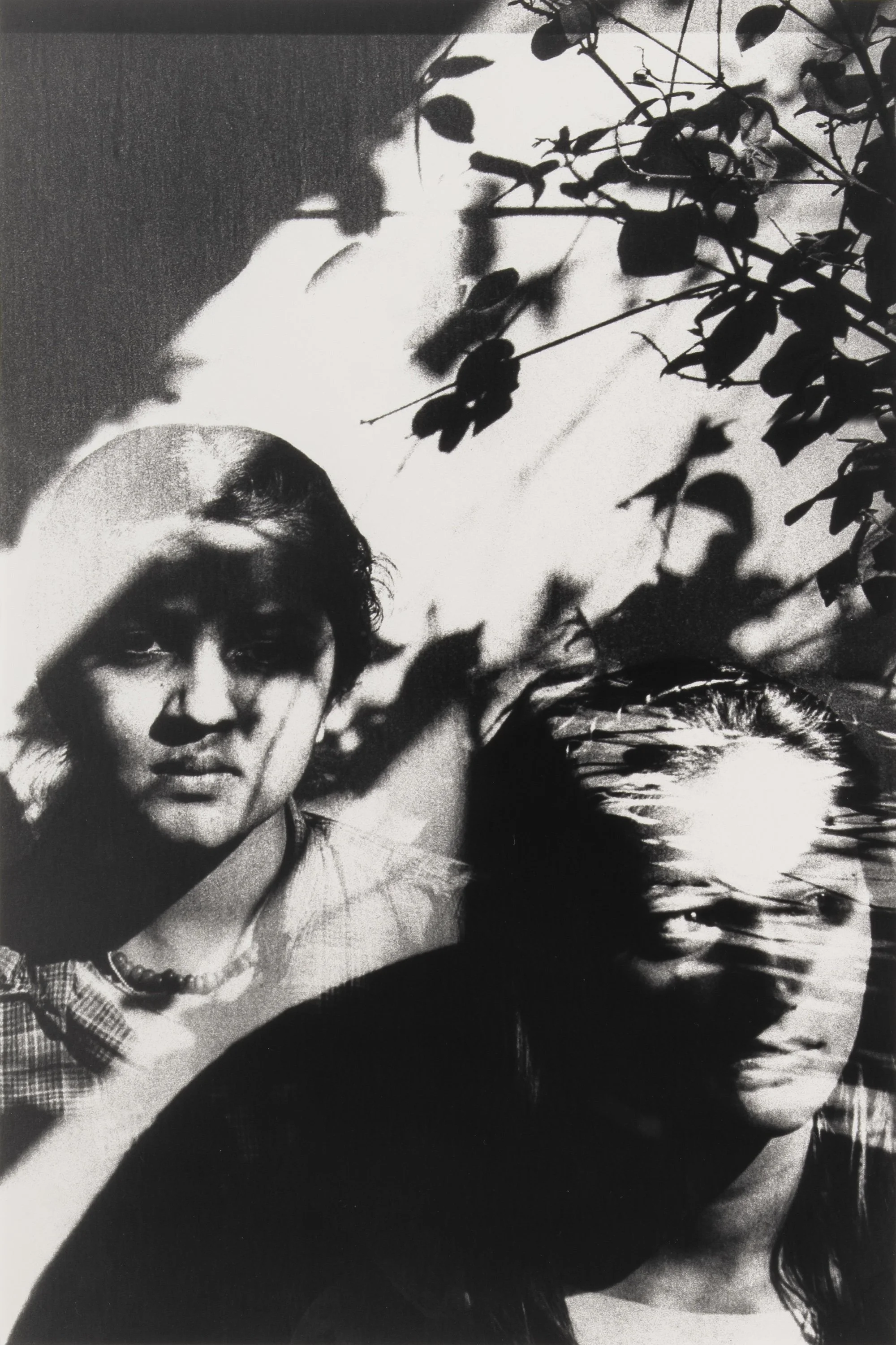 Black-and-white photograph of two overlapping faces partially obscured by leaf shadows and double exposure effects.