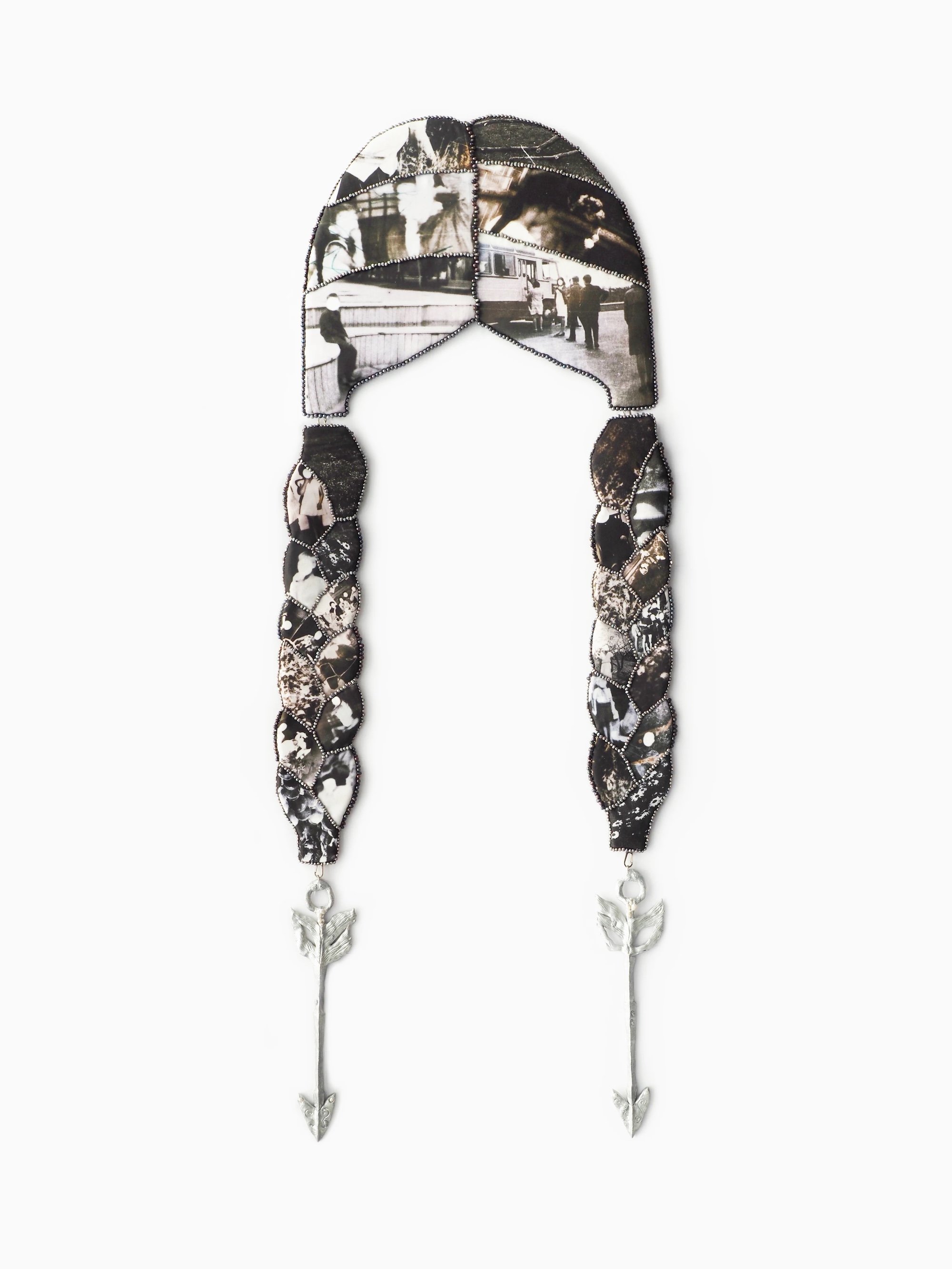 Wall sculpture resembling braided hair, composed of photo fragments bordered with beads and ending in silver arrow charms.
