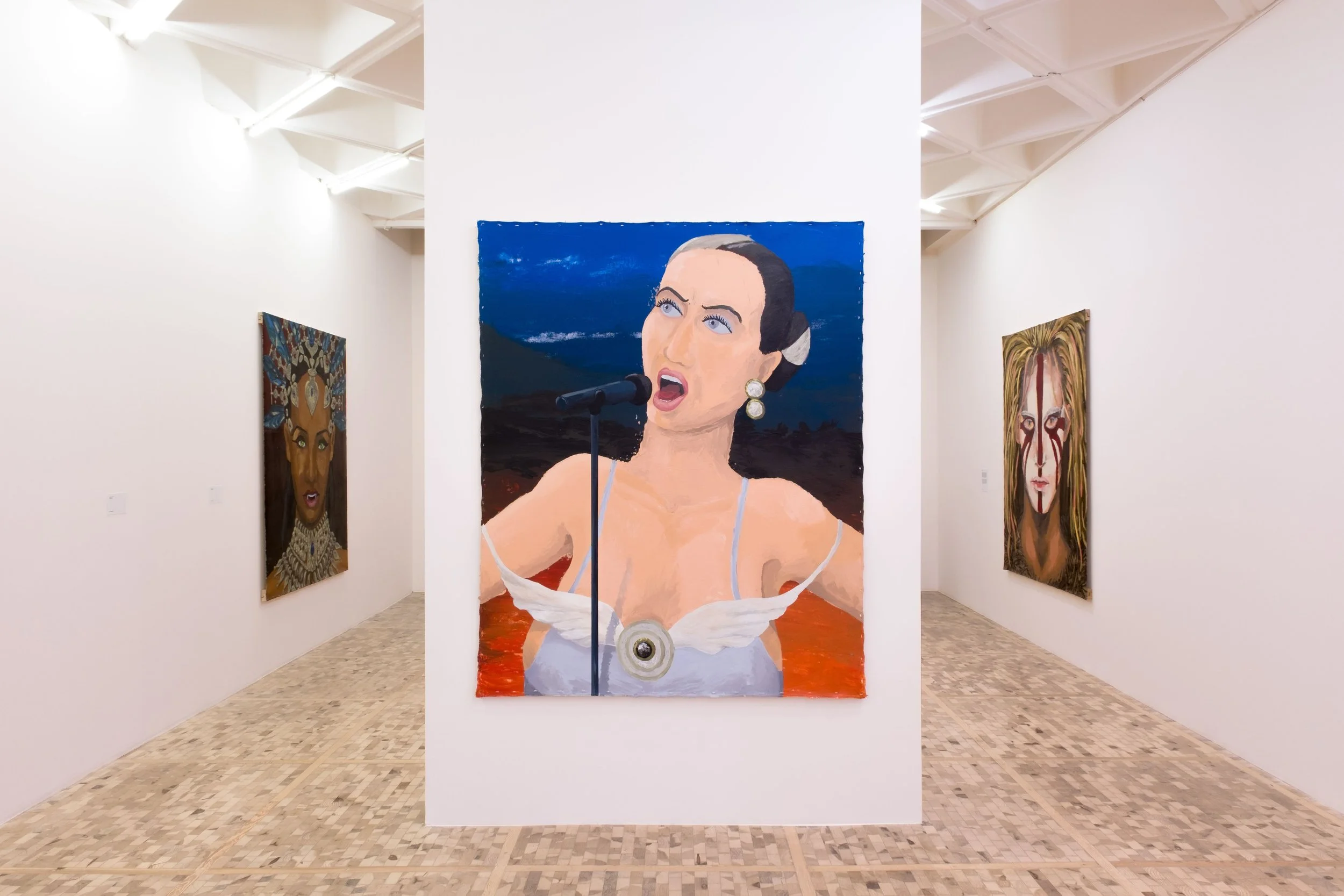 A white gallery space features three large paintings, one of ehoch hangs on a central floating wall. The paintings depict different people, the central one depicting a singer.