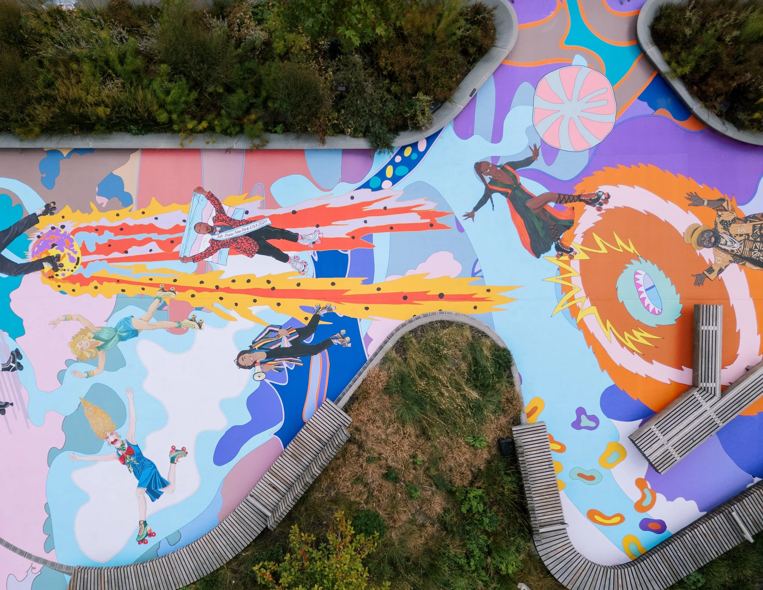 An aerial shot shows the floor of an outdoor space covered completely with colorful illustrations of people and patterns.