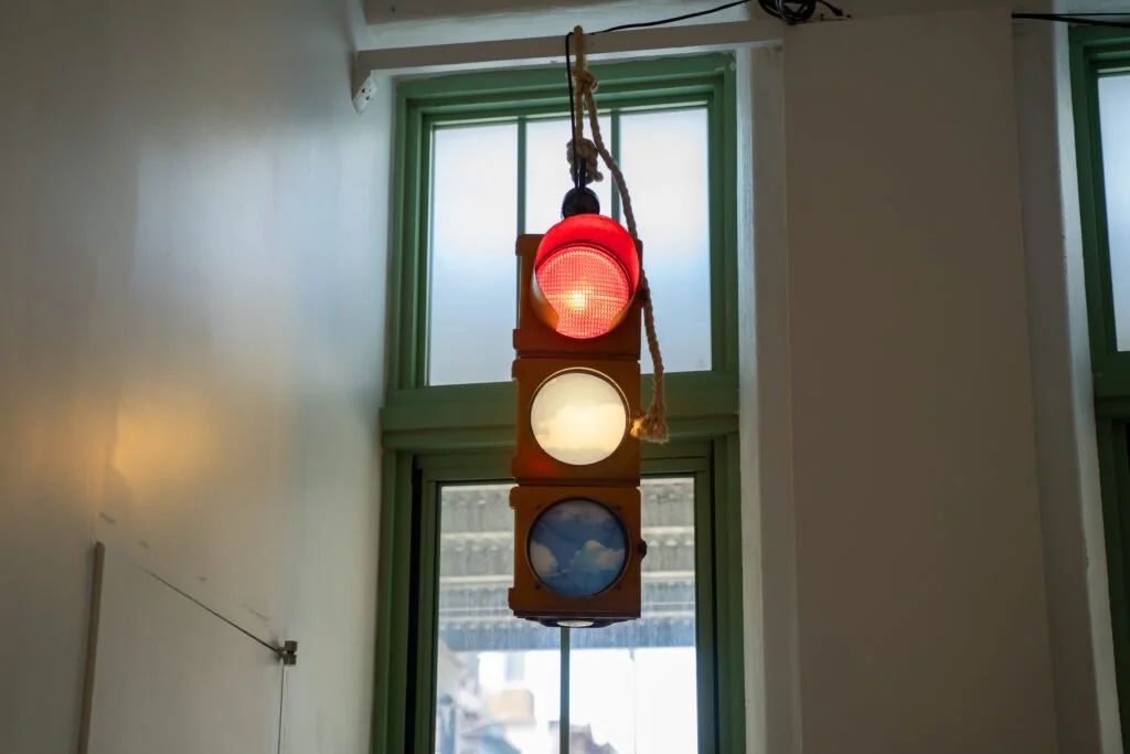 Hanging traffic light with altered signal colors displaying images of clouds instead of solid lights.