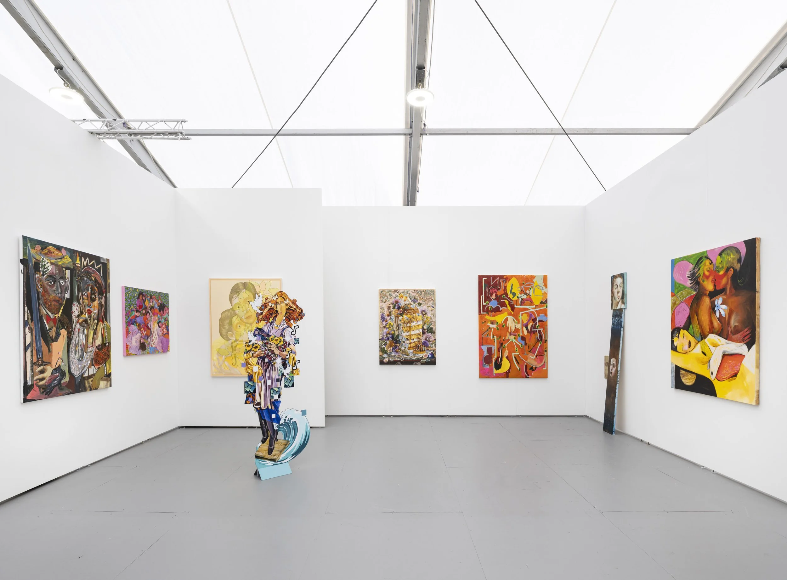 Booth displaying colorful figurative paintings and a freestanding cutout sculpture of a woman in the center.
