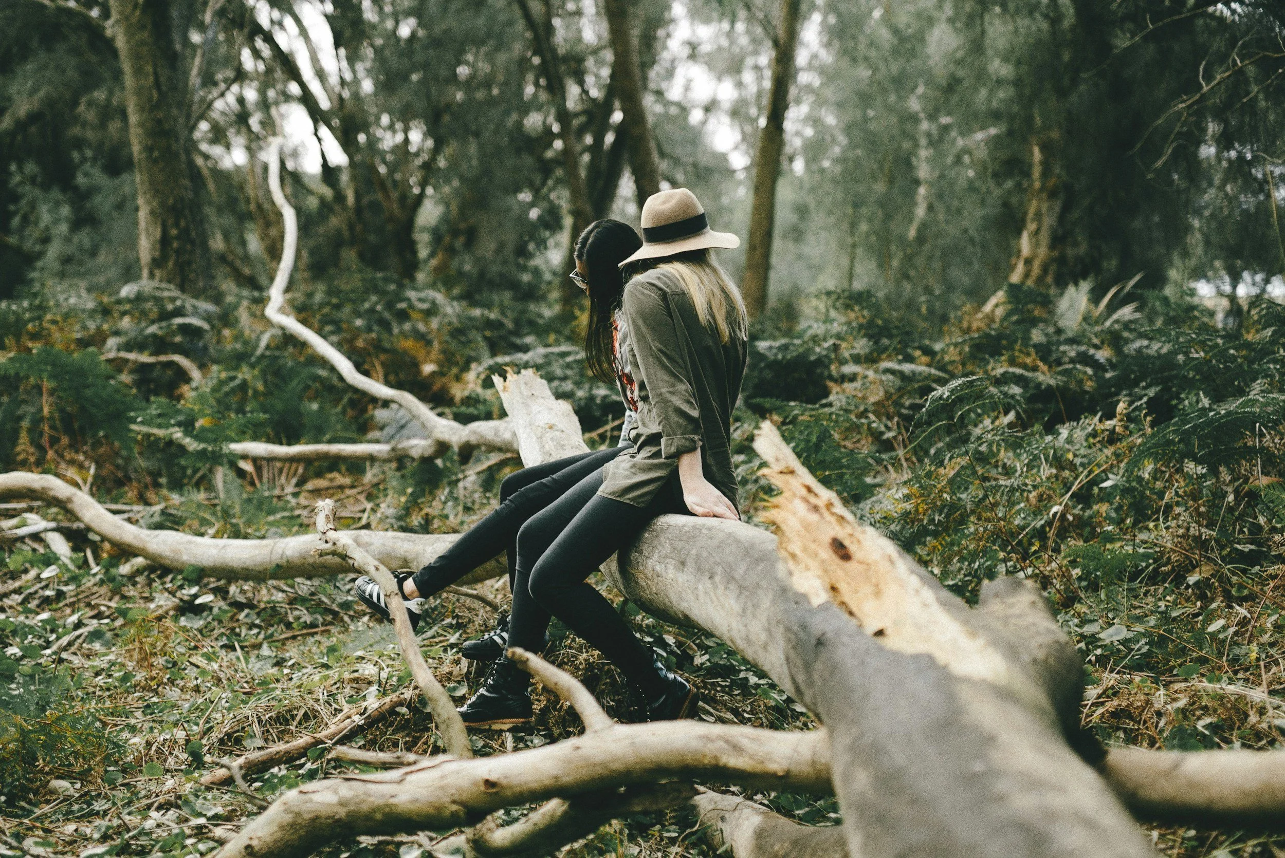 2 women sitting on a log