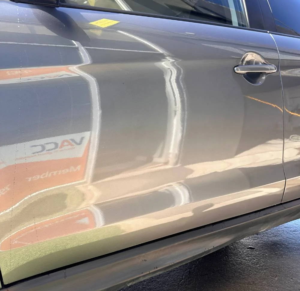 Scratch and dent repair on body of silver car by Phantom Autobody