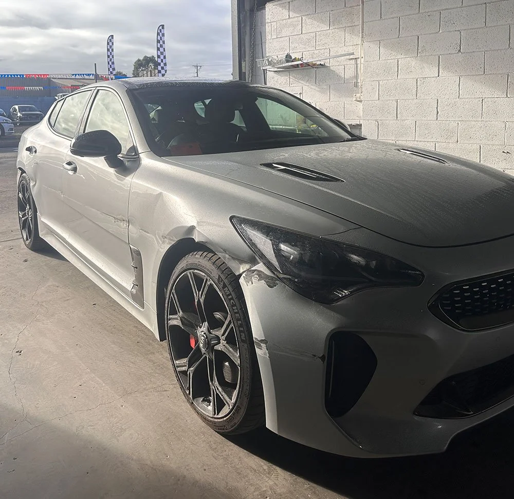 Car accident damage along the side of a silver sedan
