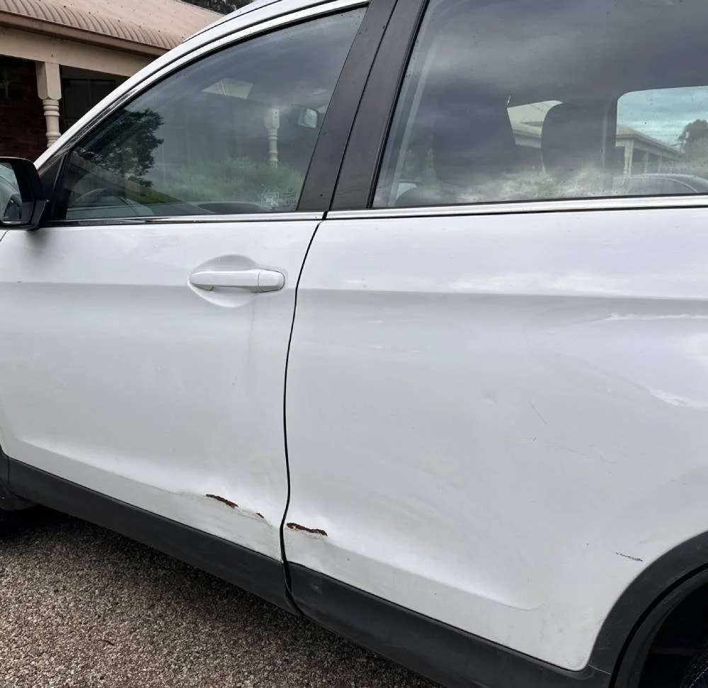 Car scratch and dent damage on body of white car