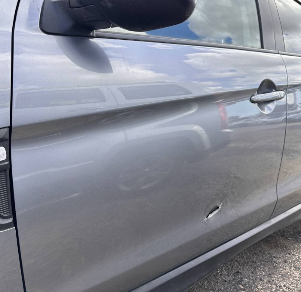 Scratch and dent damage on body of silver car