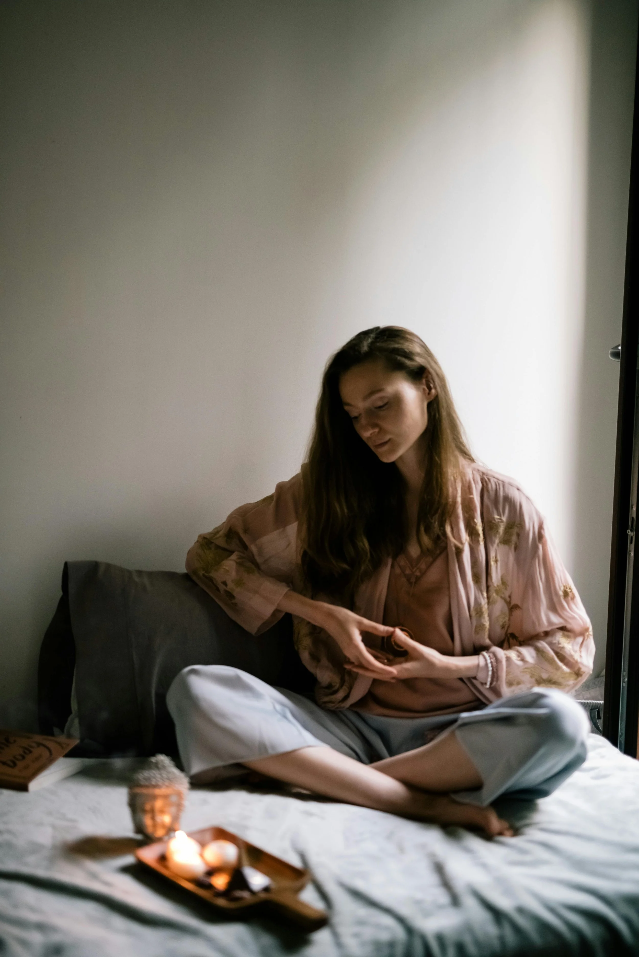 En kvinne sitter i en yogastilling i sengen sin og er i kontakt med sine åndelige elementer. Fotografi: Lee Loo Den første.