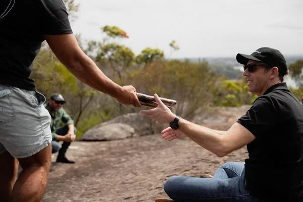 Aboriginal guide sharing a traditional tool with a corporate participant on Country in Sydney