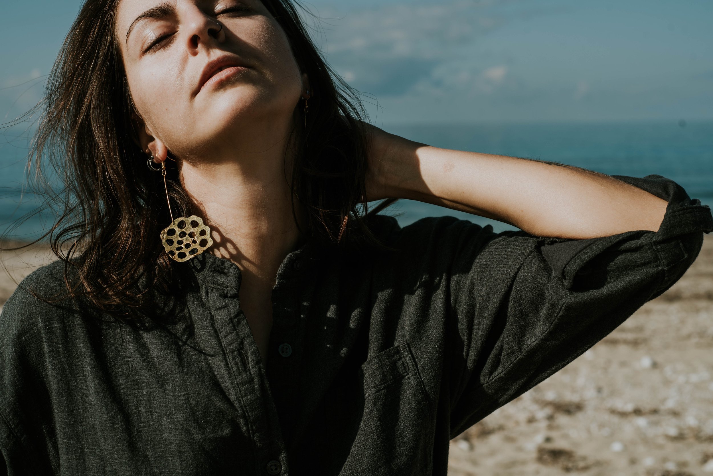 Model wearing bold brass lotus seedpod earrings, large elegant statement jewelry inspired by organic seedpod forms