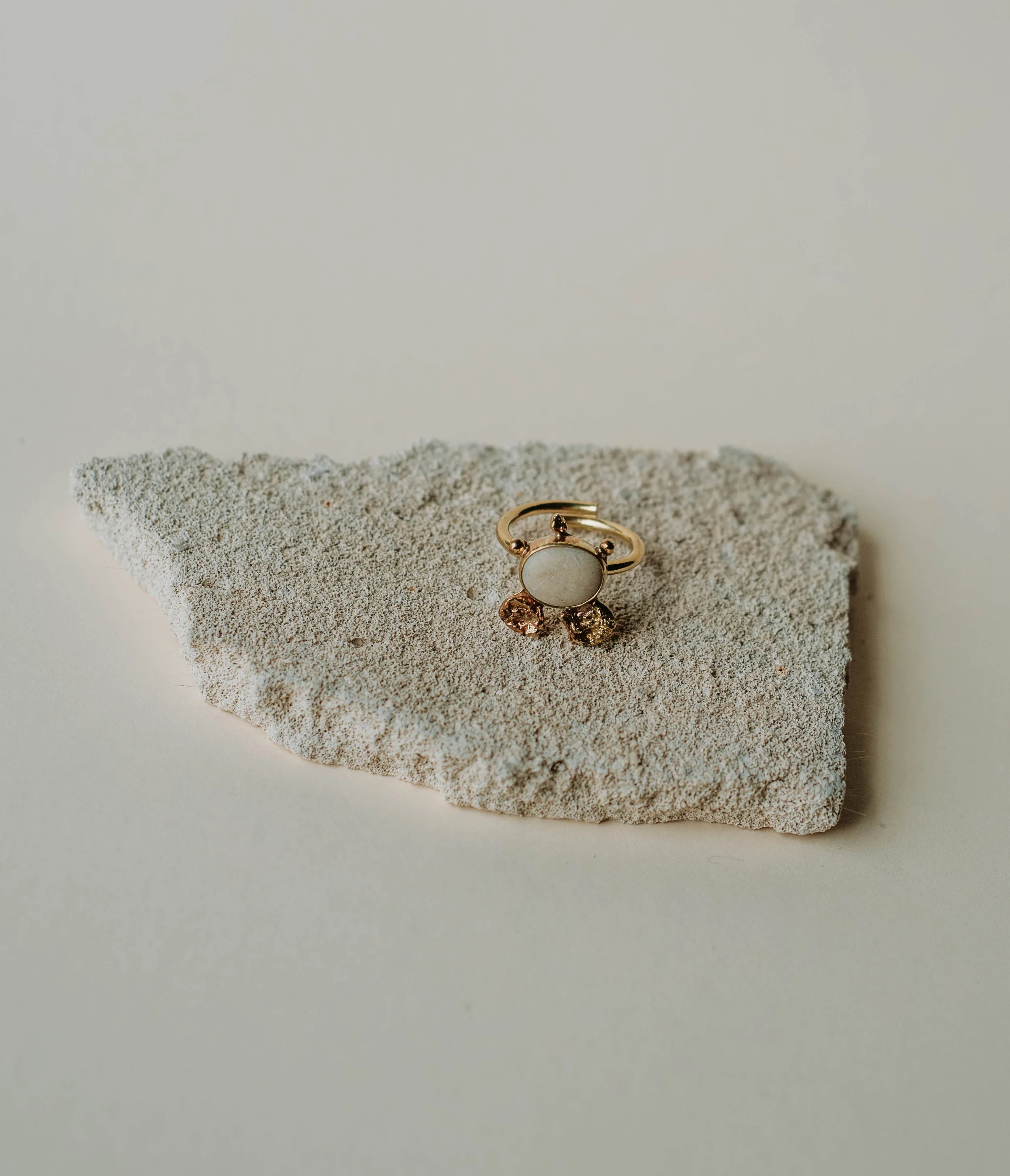 Adjustable brass ring with a small white pebble from the Lefkada coast and molten brass details, handmade one-of-a-kind jewelry