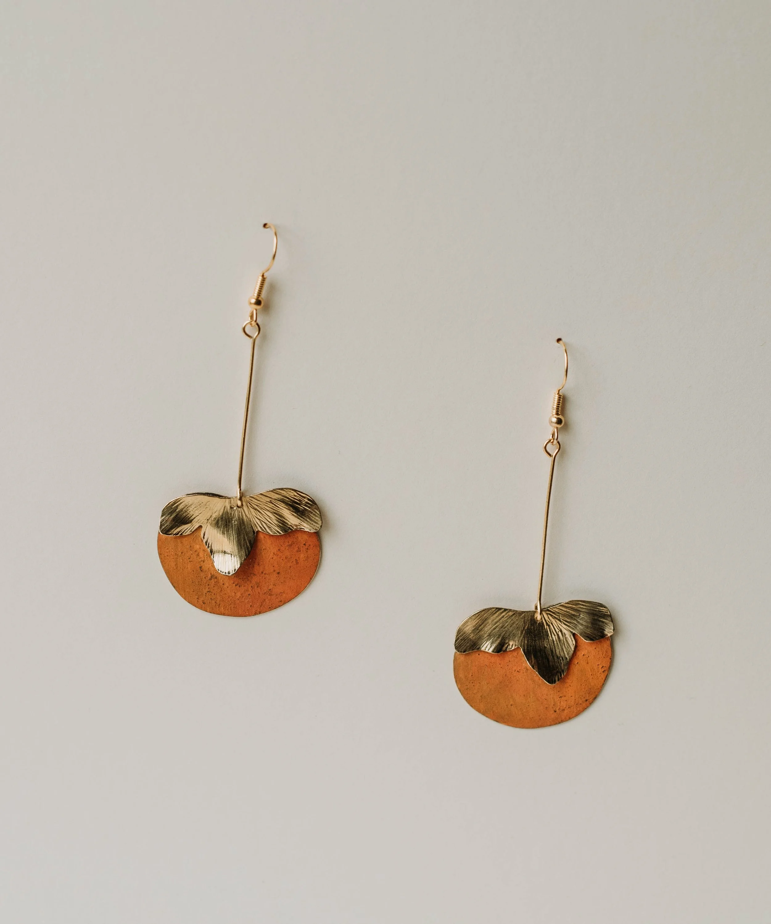 Handmade brass persimmon earrings inspired by Mediterranean winter gardens. Joyful, warm-toned statement jewelry with an elegant, playful feel.