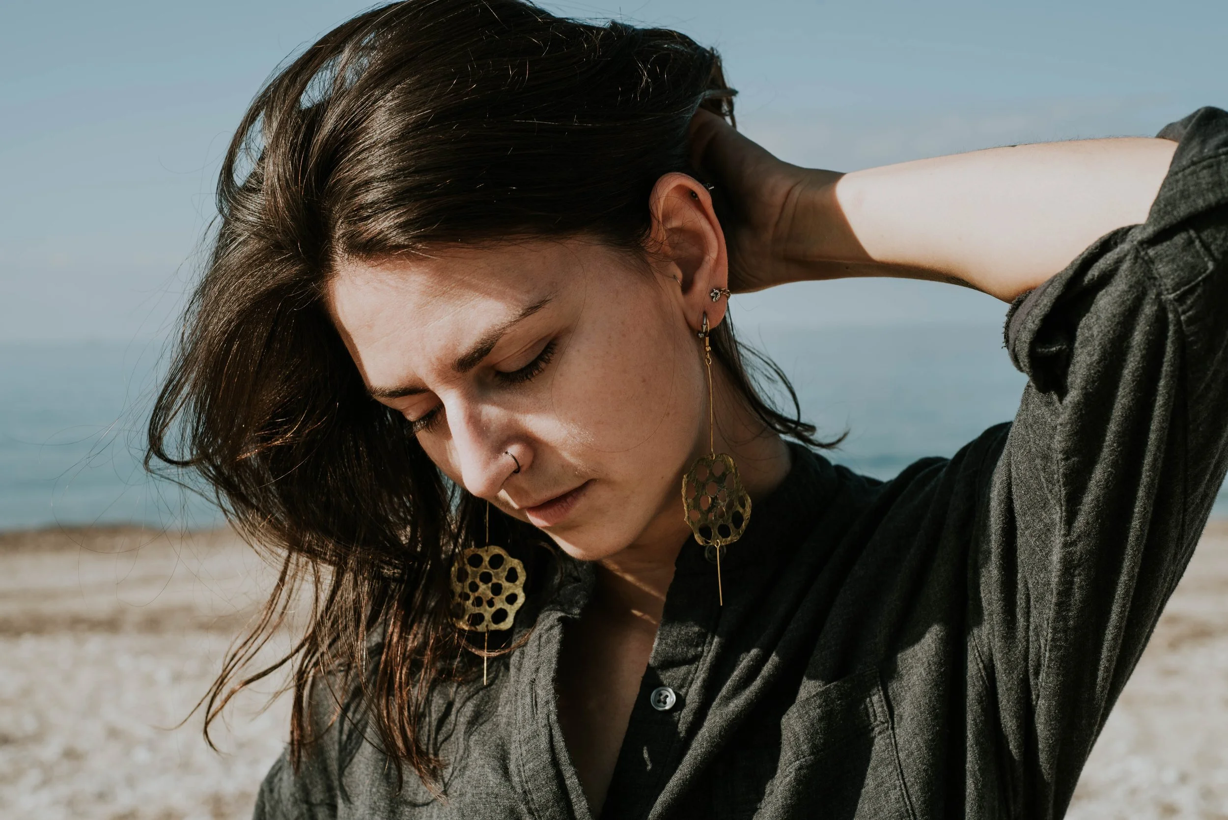Model wearing bold brass lotus seedpod earrings, large elegant statement jewelry inspired by organic seedpod forms