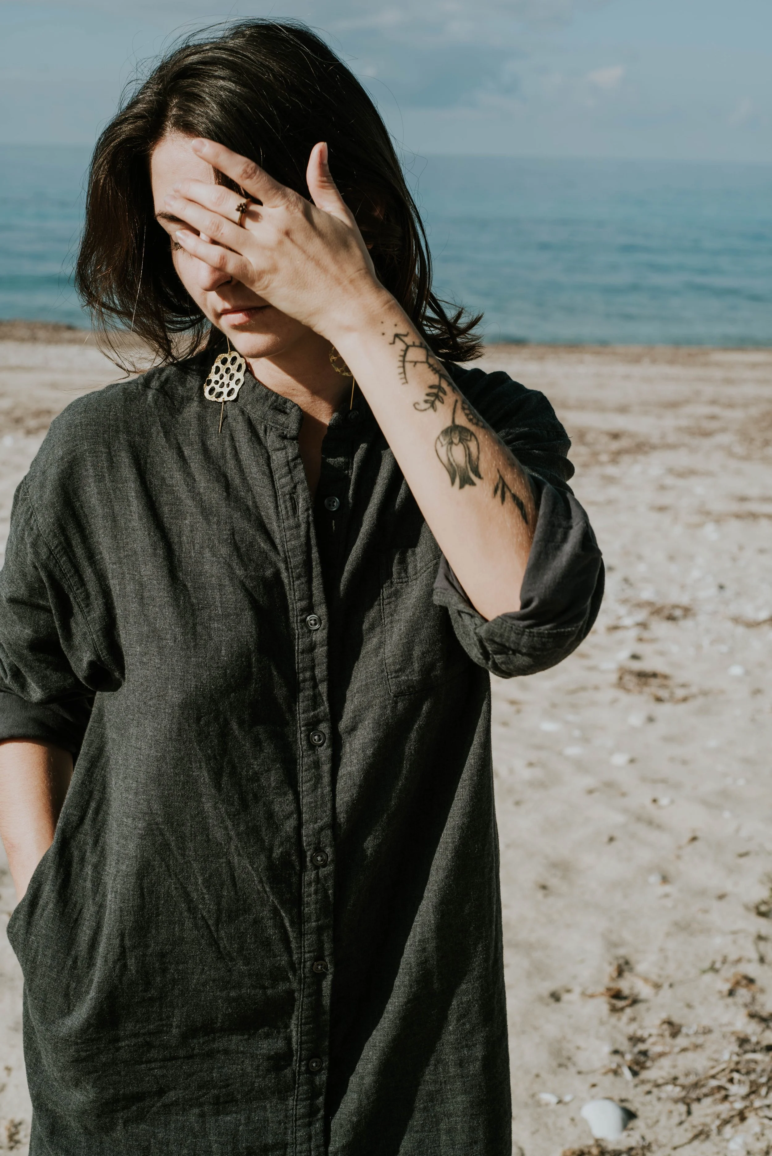 Model wearing bold brass lotus seedpod earrings, large elegant statement jewelry inspired by organic seedpod forms