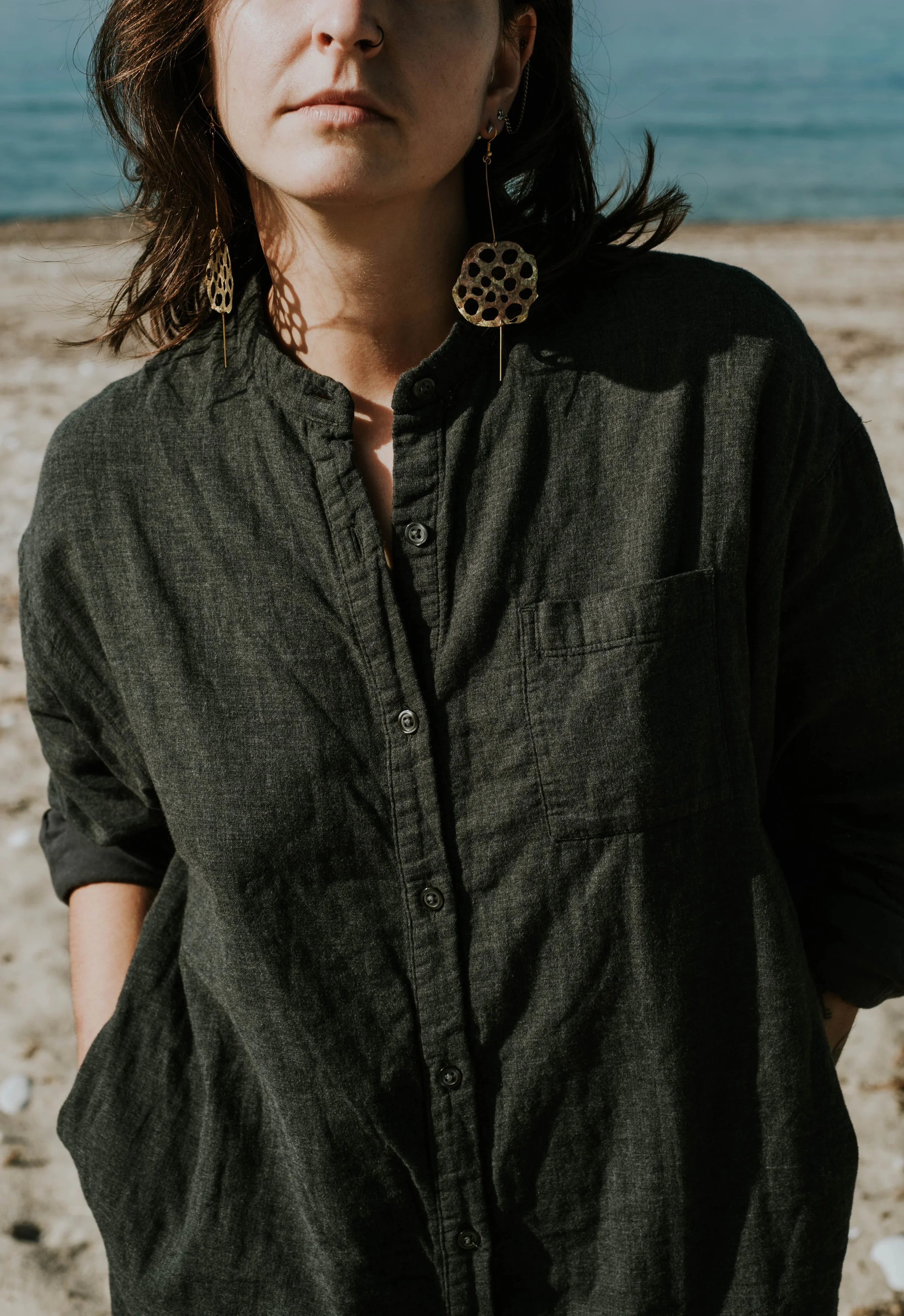 Model wearing bold brass lotus seedpod earrings, large elegant statement jewelry inspired by organic seedpod forms