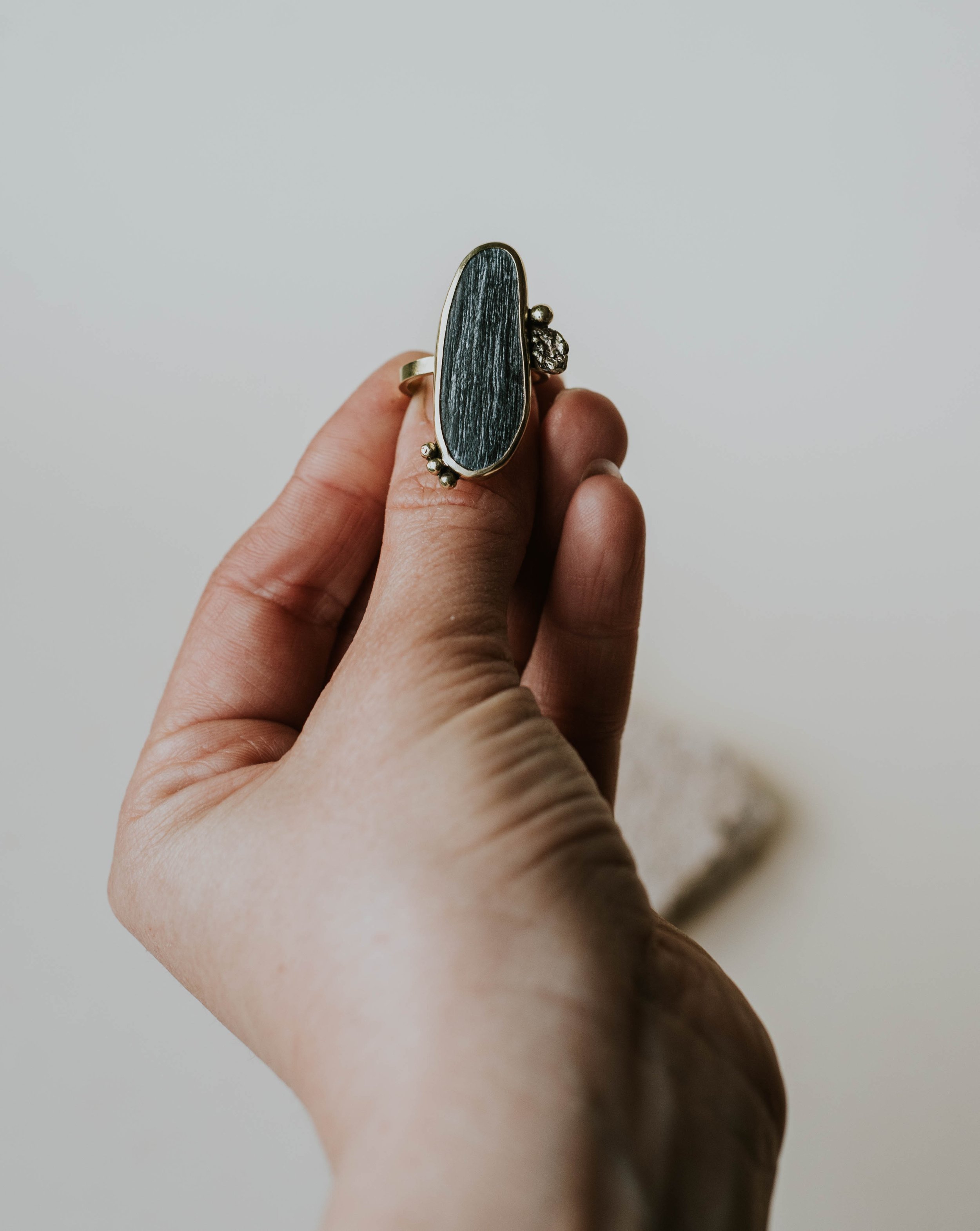 Adjustable brass ring with 3 x 1 cm black pebble from South Italian coast and molten brass detail.