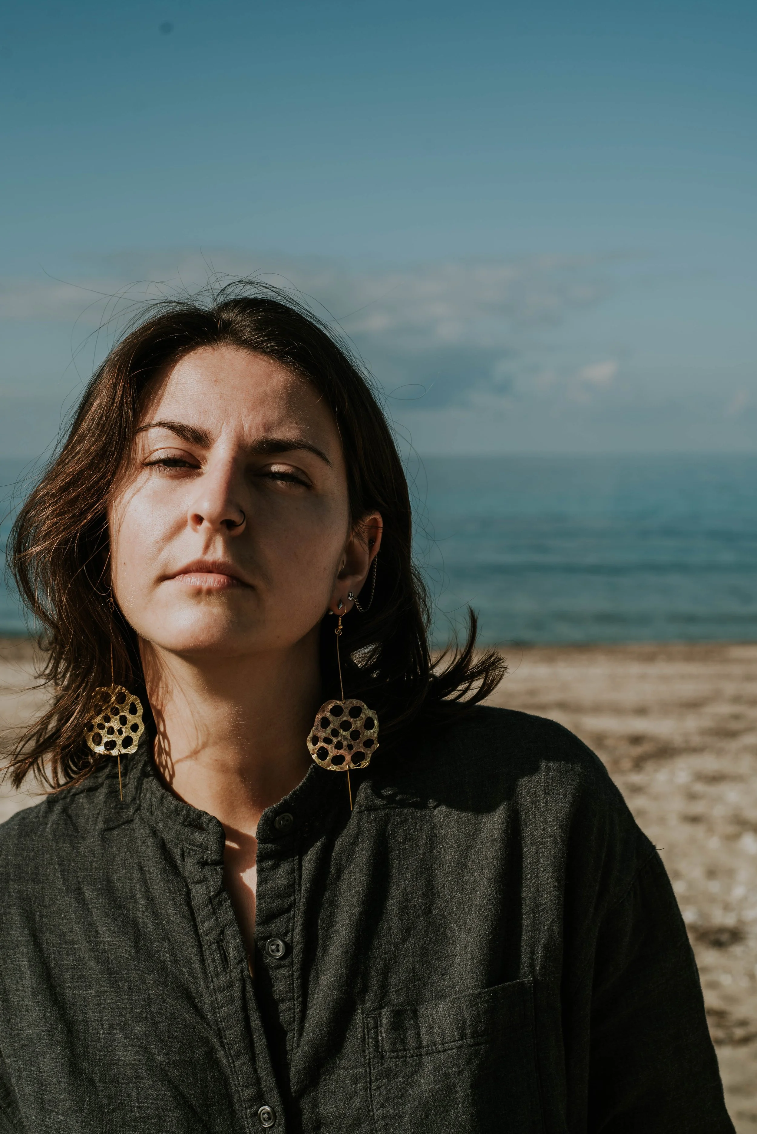 Model wearing bold brass lotus seedpod earrings, large elegant statement jewelry inspired by organic seedpod forms