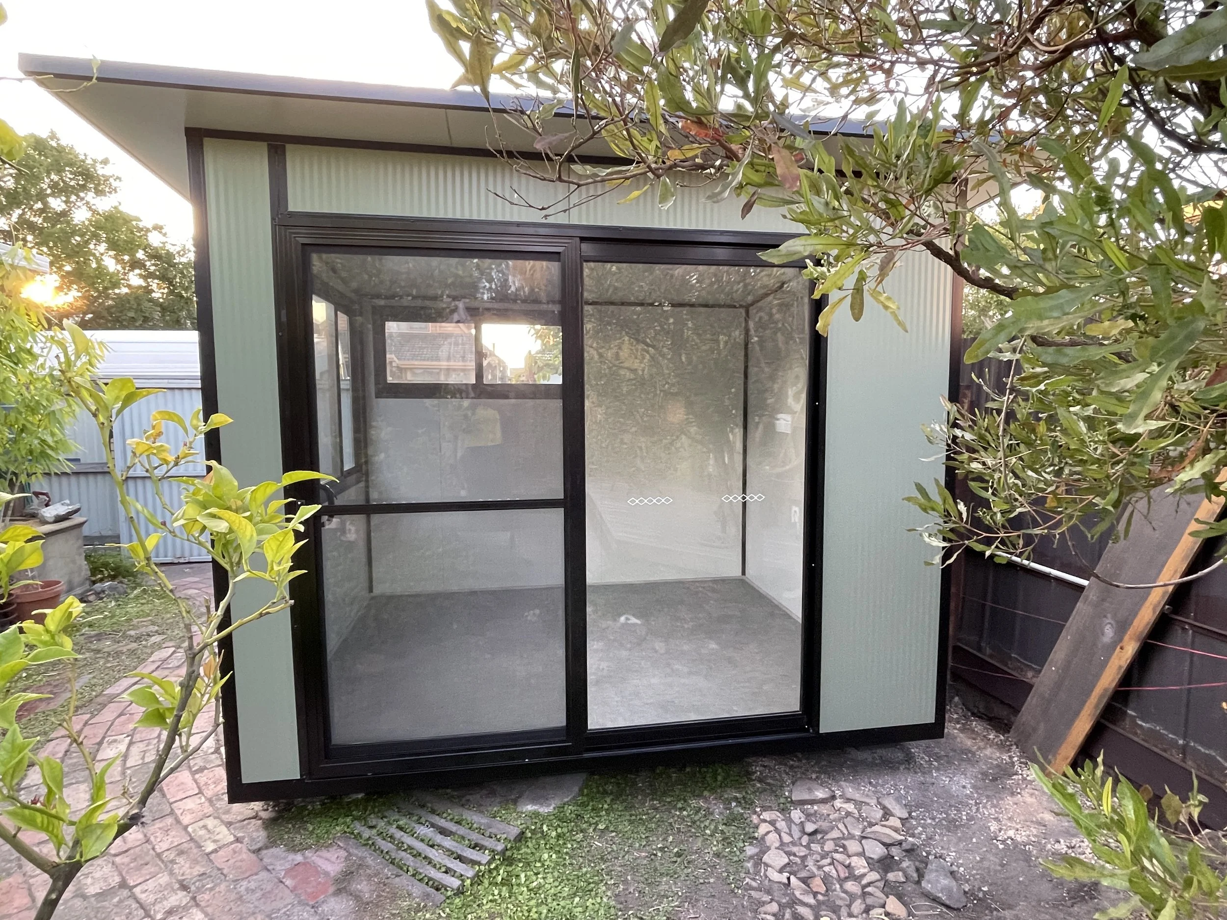 Lifestyle Backyard Pods garden studio finished in Pale Eucalypt Colorbond steel with Satinline exterior cladding and sliding glass doors.