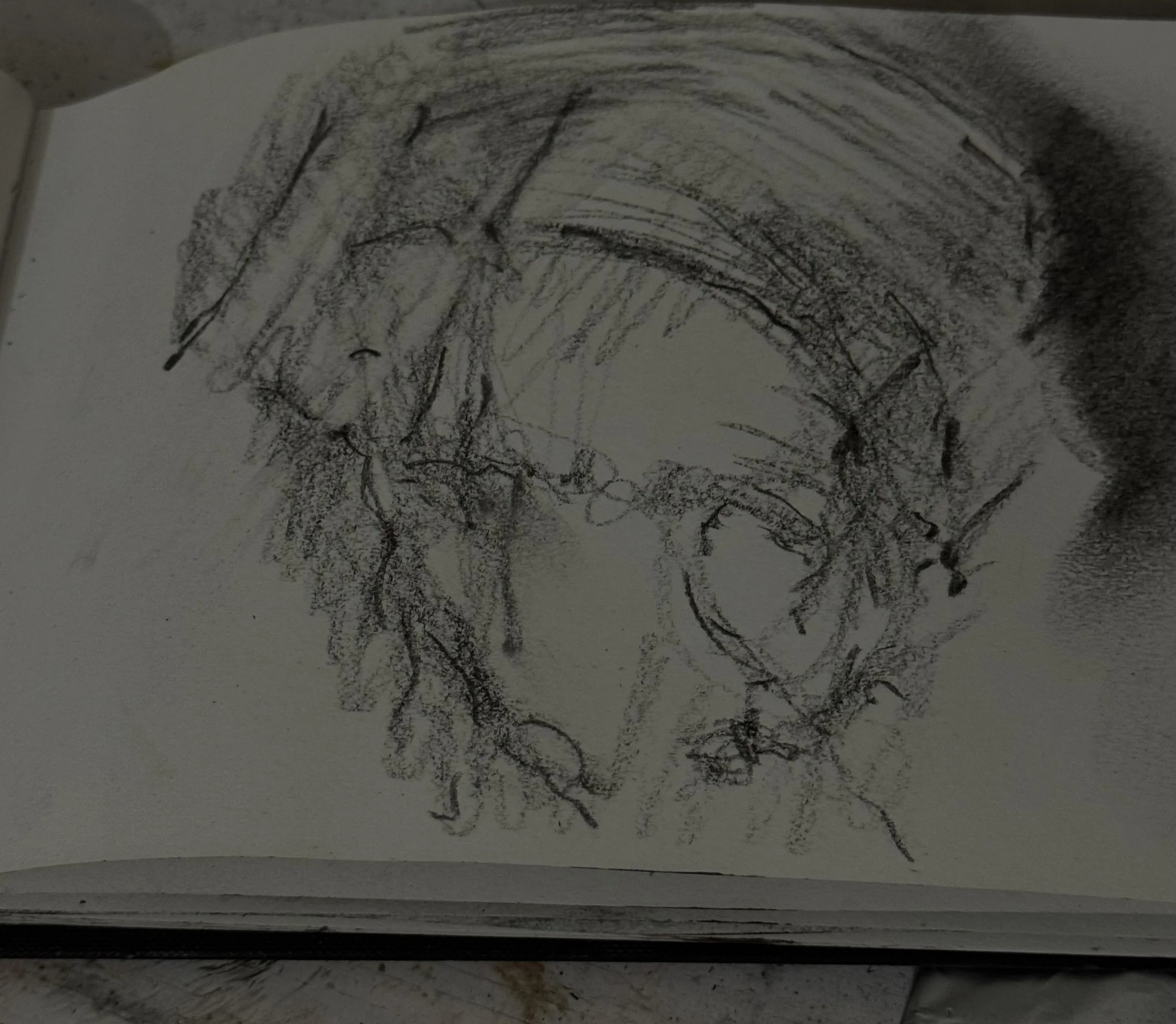 A sketch of a person's face, showing facial features with rough, loose lines, on a white piece of paper.