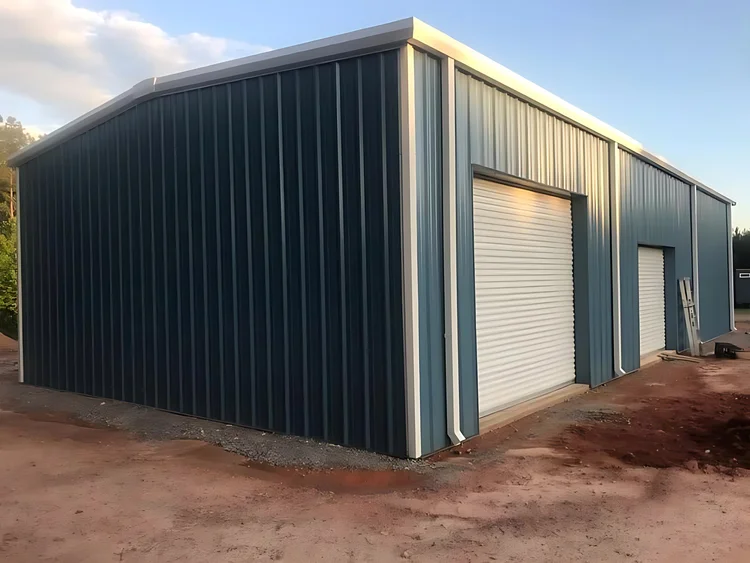 Blue-gray steel shop with white trim and roll-up doors