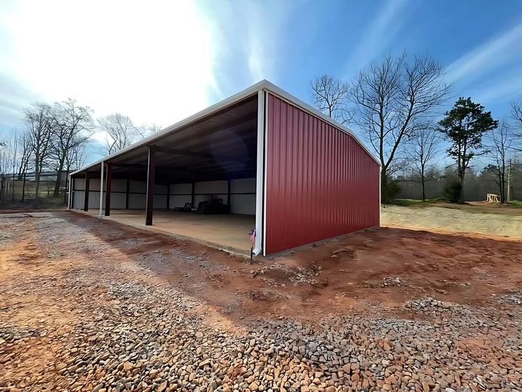Red open-sided equipment shed with a gravel floor