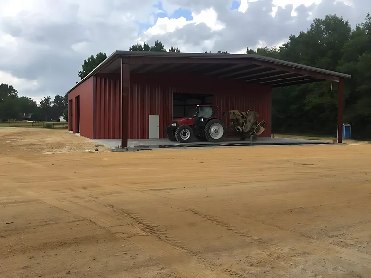 Red steel equipment barn with a tractor under the lean-to