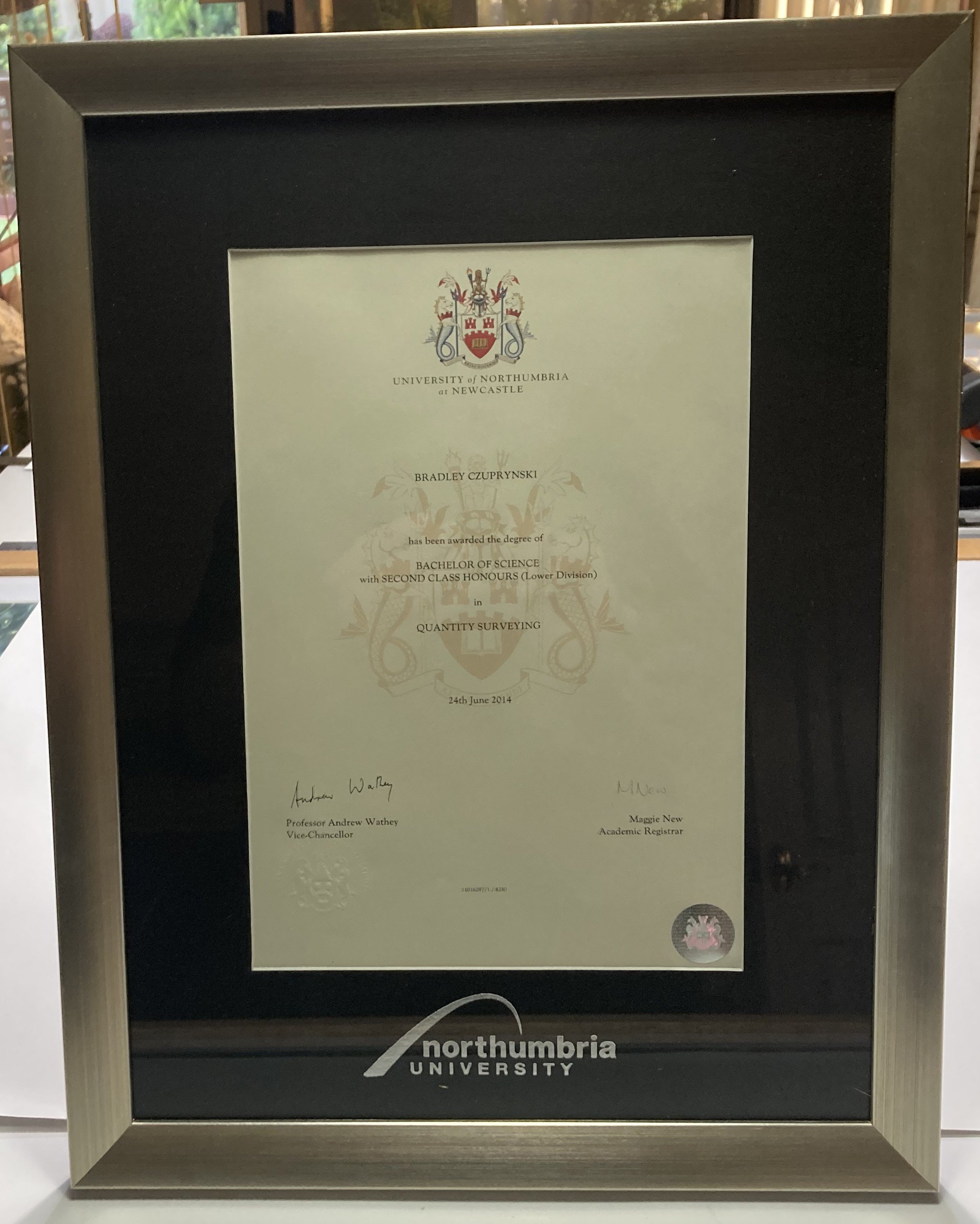 Framed degree certificate from Northumbria University awarded to Bradley Czuprynski for a Bachelor of Science in Quantity Surveying, dated June 24, 2014.