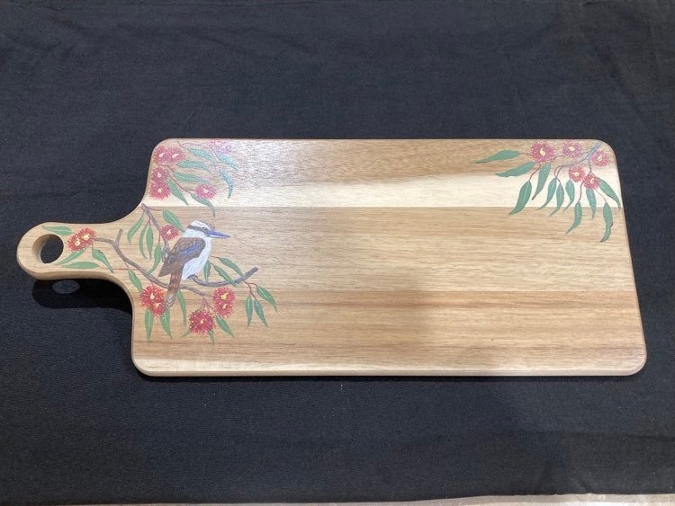 A rectangular wooden chese board with a handle, decorated with a painted bird and flowers in the corner.